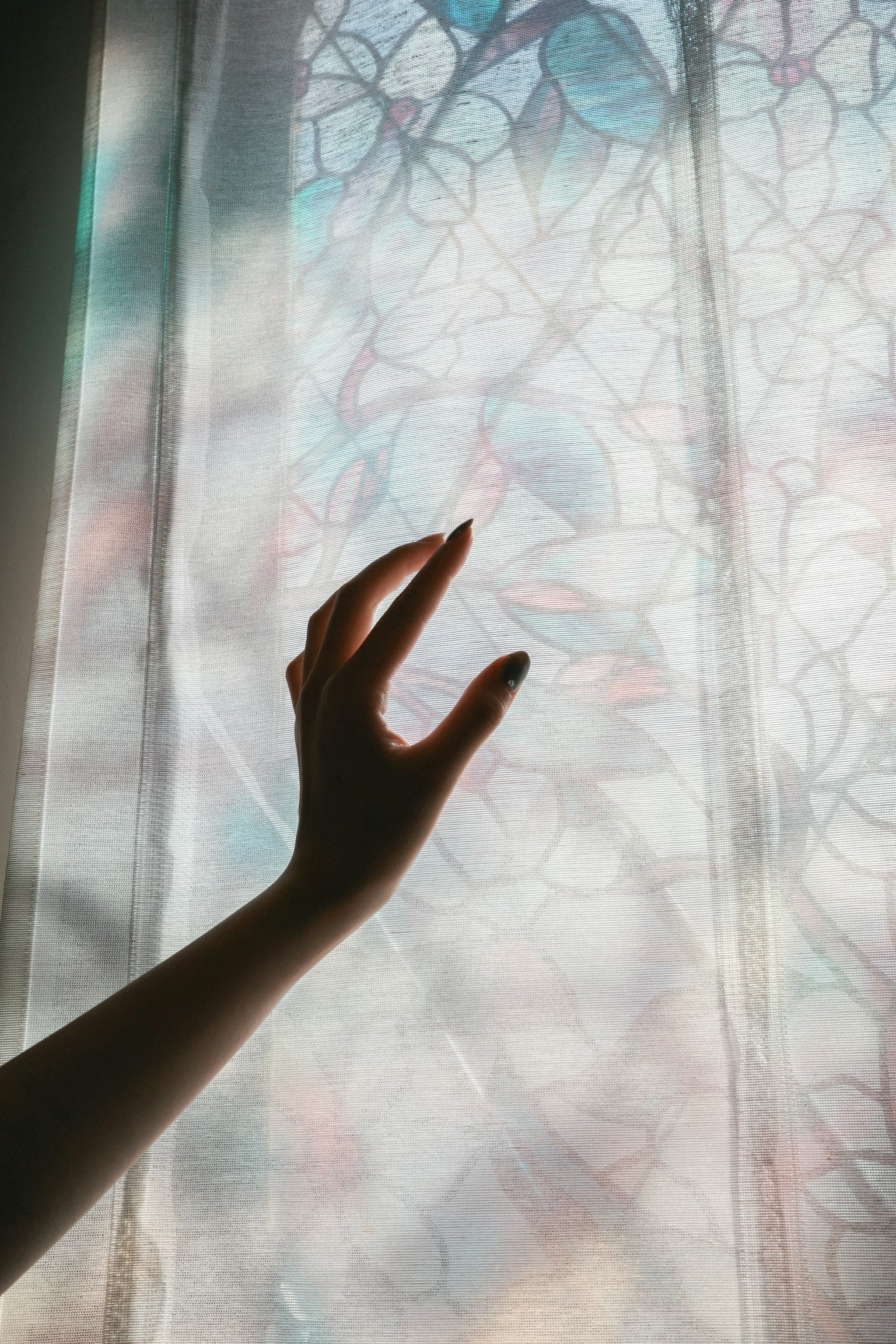 手がカラフルなステンドグラスの窓に触れようとしているシーン