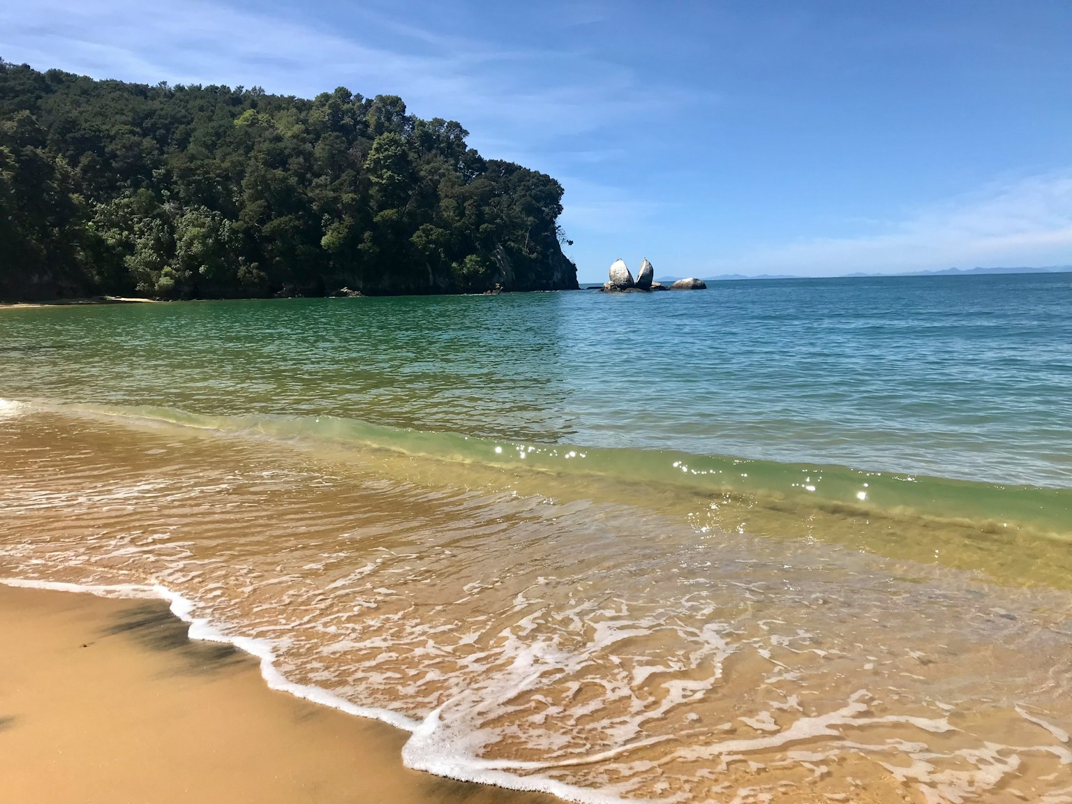 Pemandangan indah laut biru dan pantai berpasir dengan tebing hijau