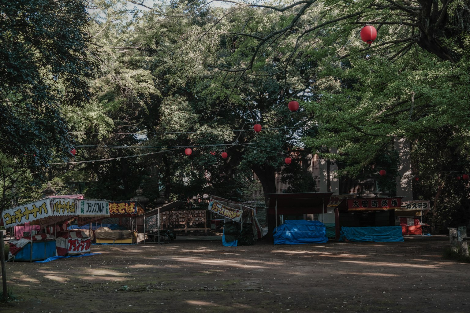 Puestos coloridos en un parque verde con faroles rojos colgantes