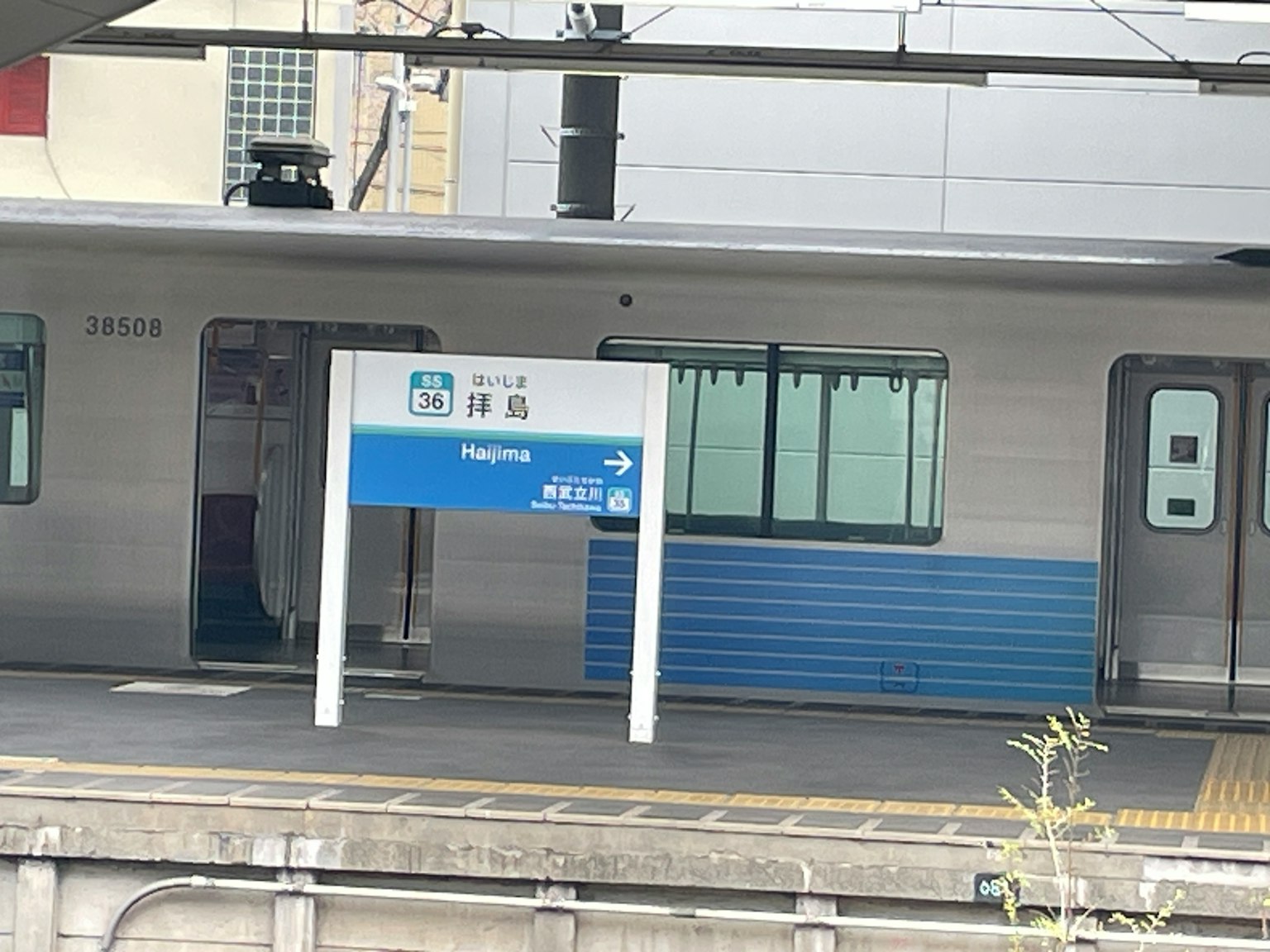 Sân ga tàu với biển báo màu xanh và tòa nhà màu trắng