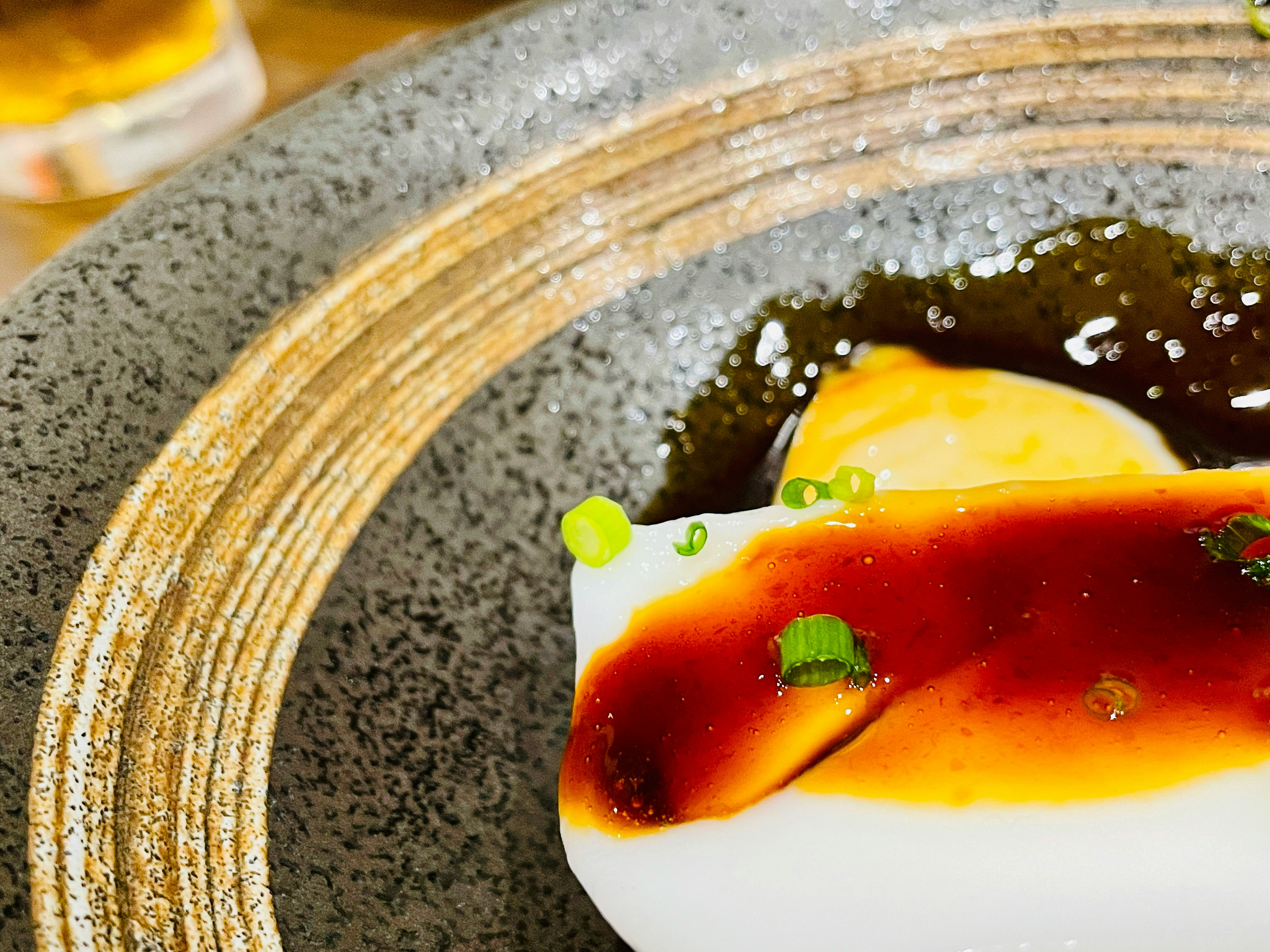Spoonful of rich pudding with glossy sauce