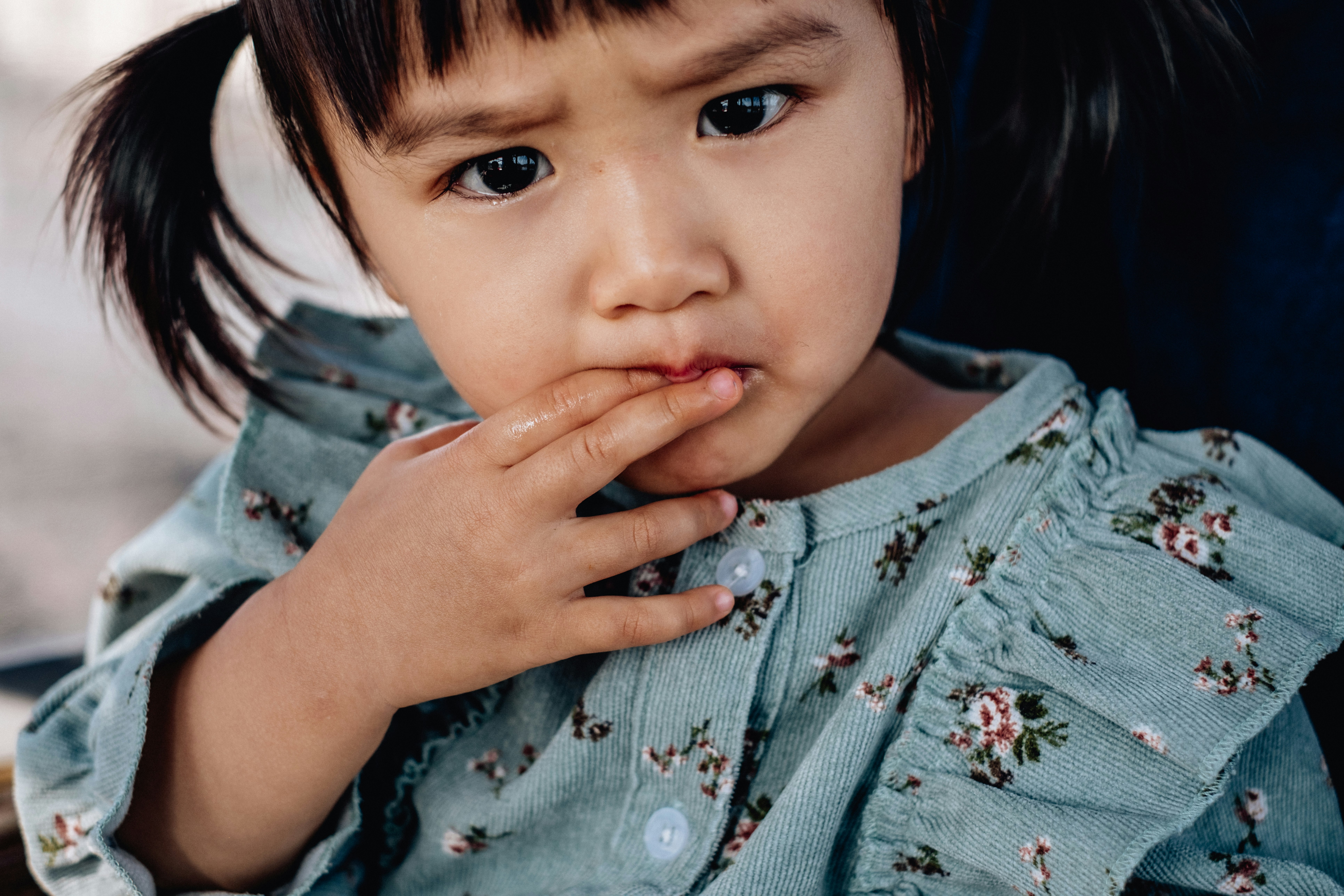 Primer plano de un niño pequeño con la mano cerca de la boca