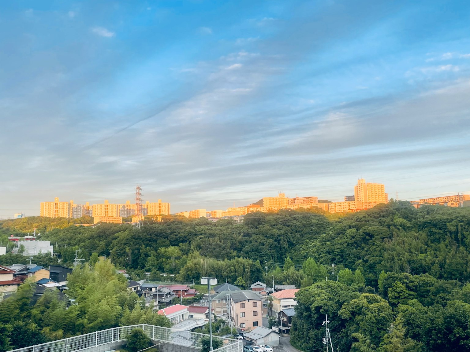 日落城市景观，背景有绿丘和建筑