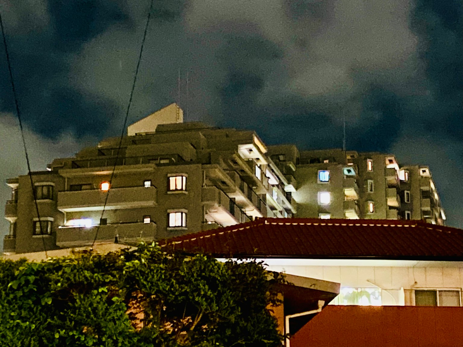 Bangunan apartemen modern yang diterangi di malam hari dengan langit mendung