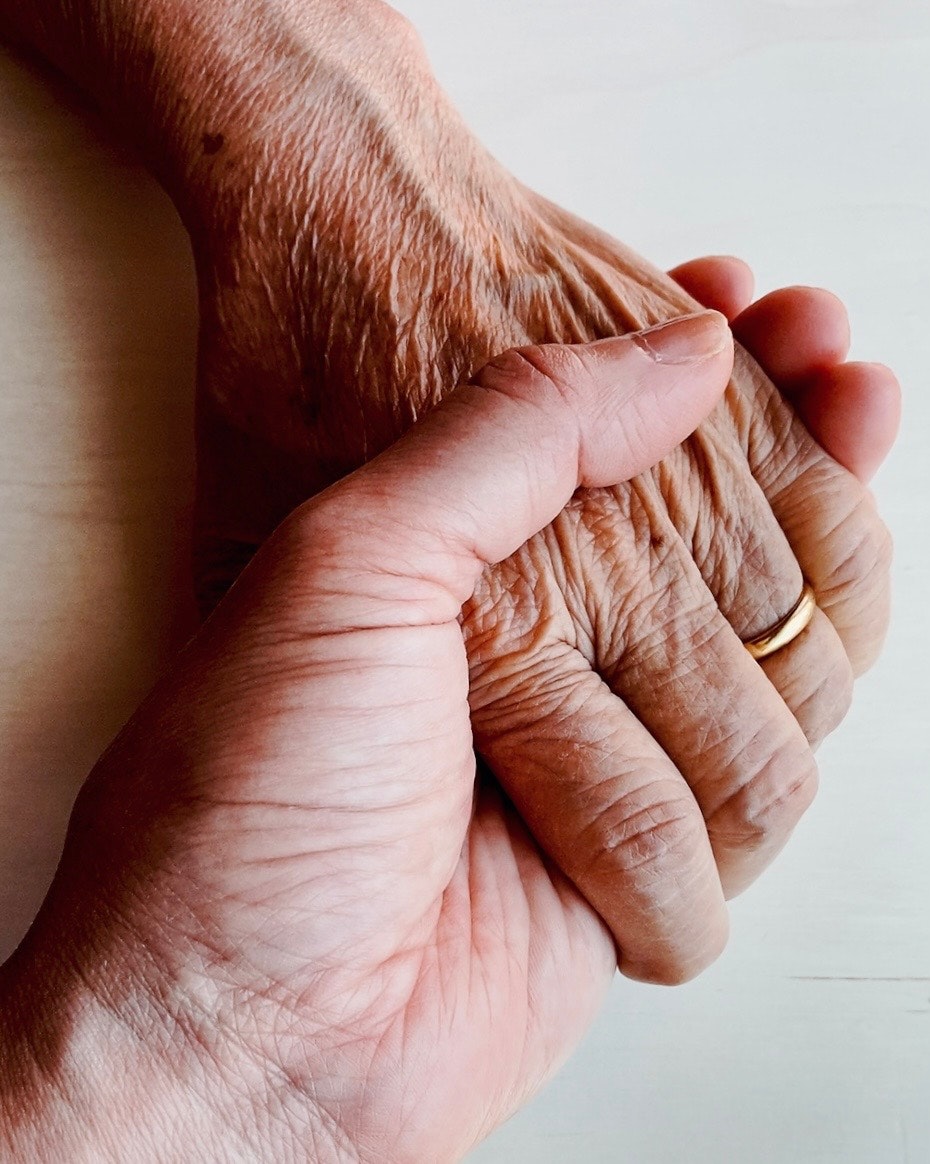 A warm moment of two hands clasped together one hand is aged with visible wrinkles the other is younger