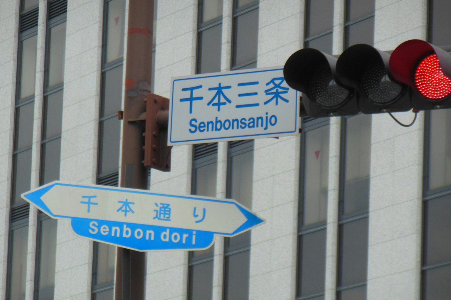 Städtische Szene mit einer roten Ampel und blauen Straßenschildern