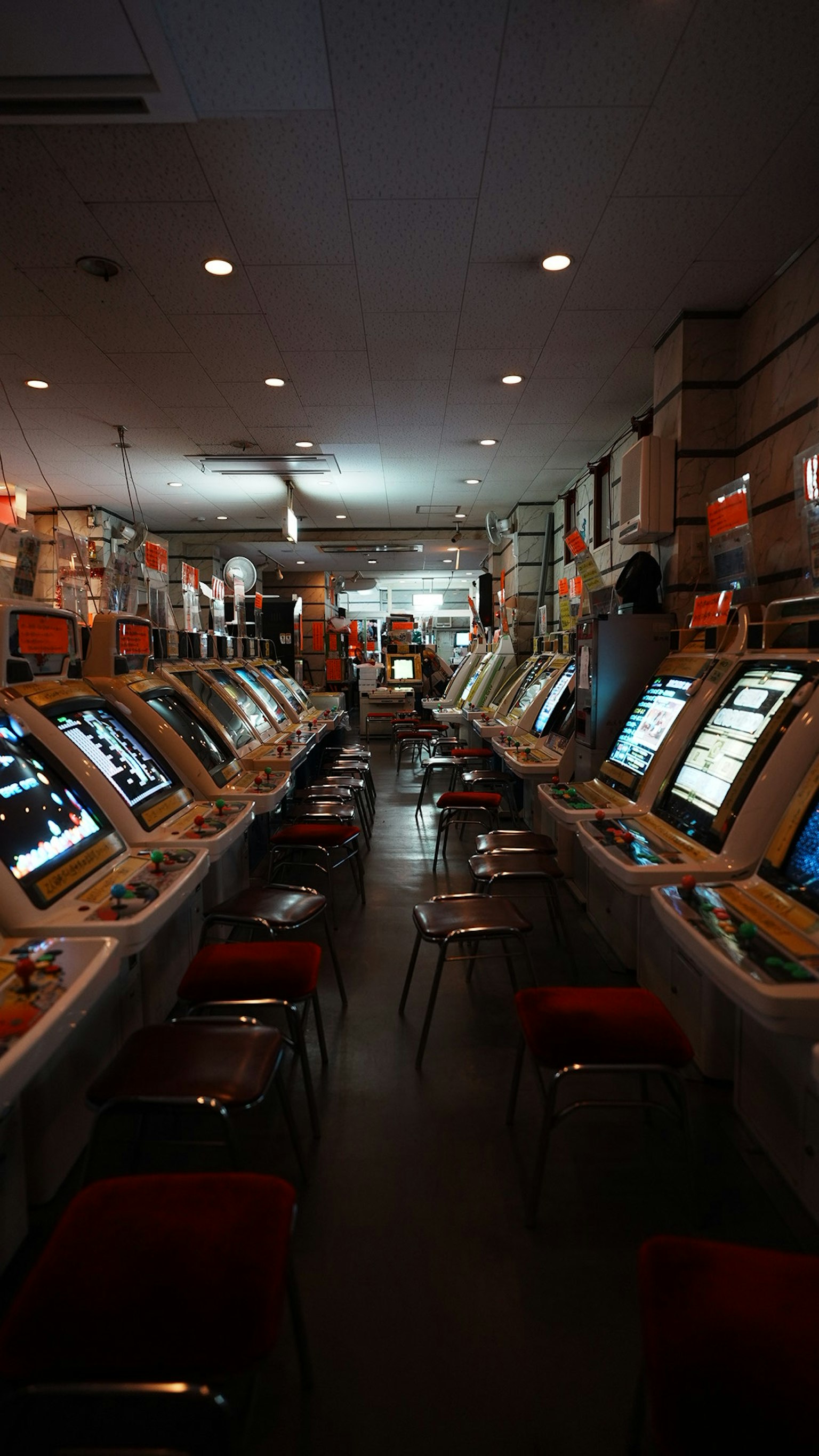 Interior of a casino with rows of slot machines bright lighting and red chairs
