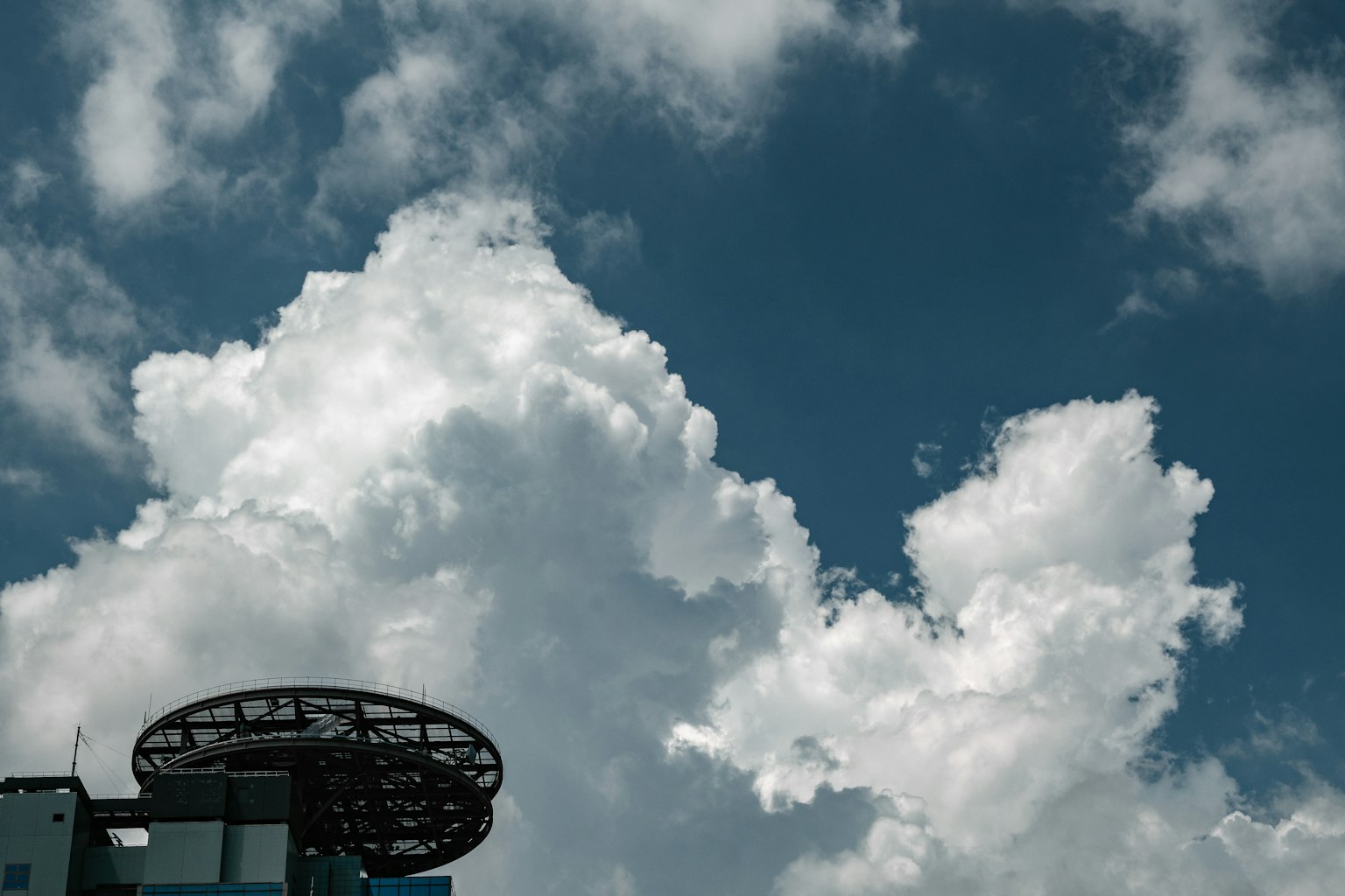 Eine Ansicht von weißen Wolken gegen einen blauen Himmel mit einem Teil eines Gebäudes sichtbar