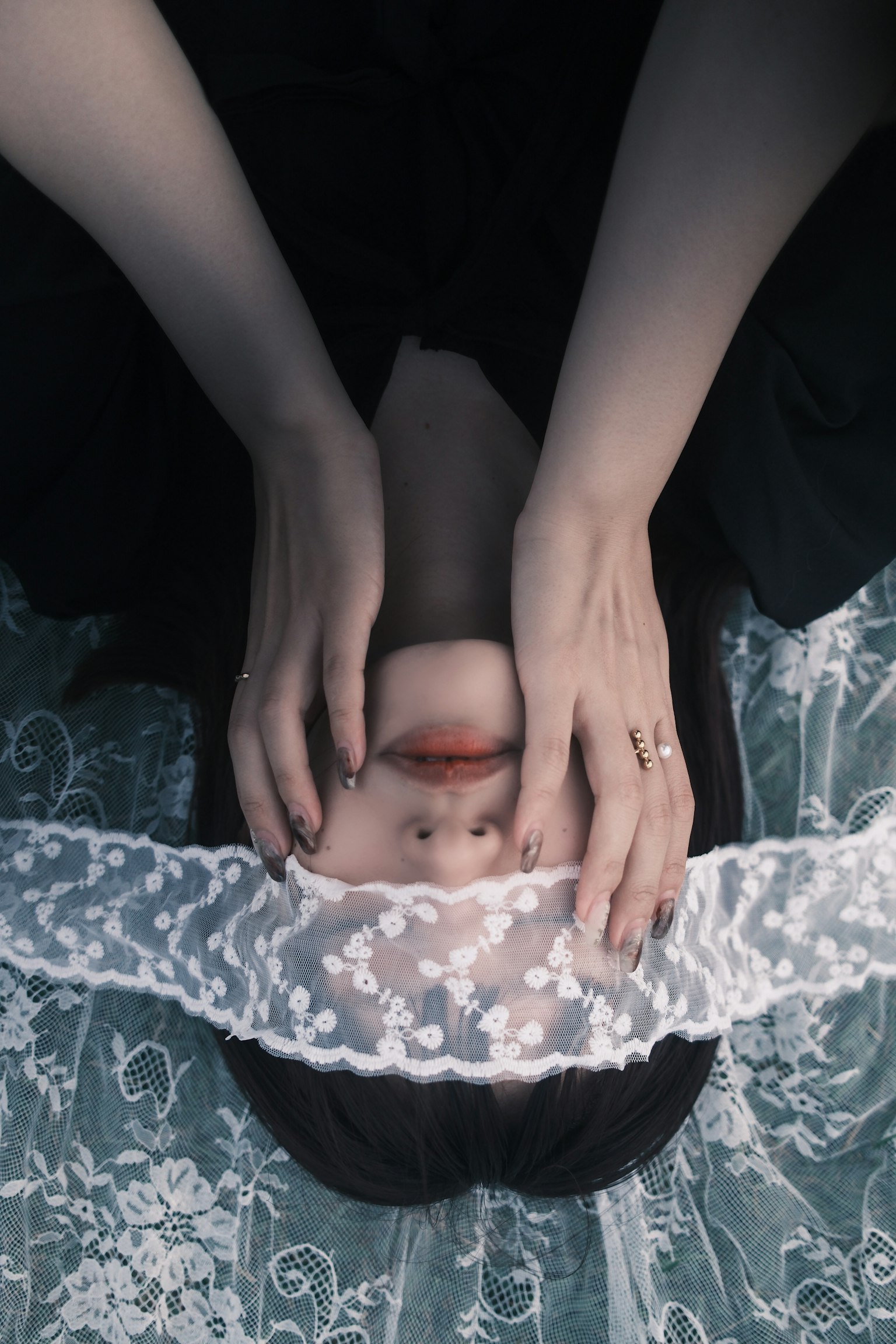 白いレースのベールを持つ女性が顔を隠しているシーン