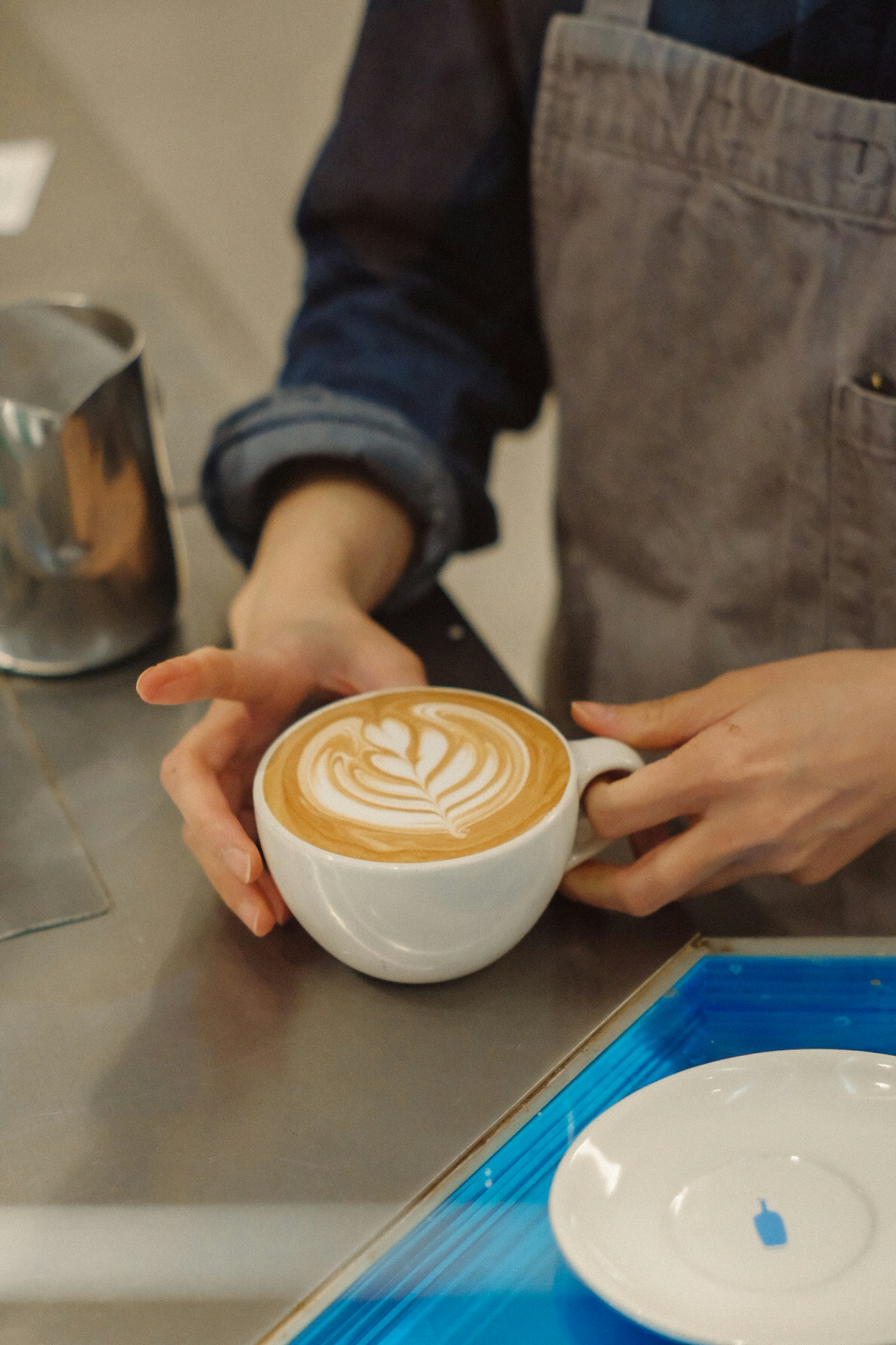 Un barista sosteniendo una taza de café con arte latte intrincado