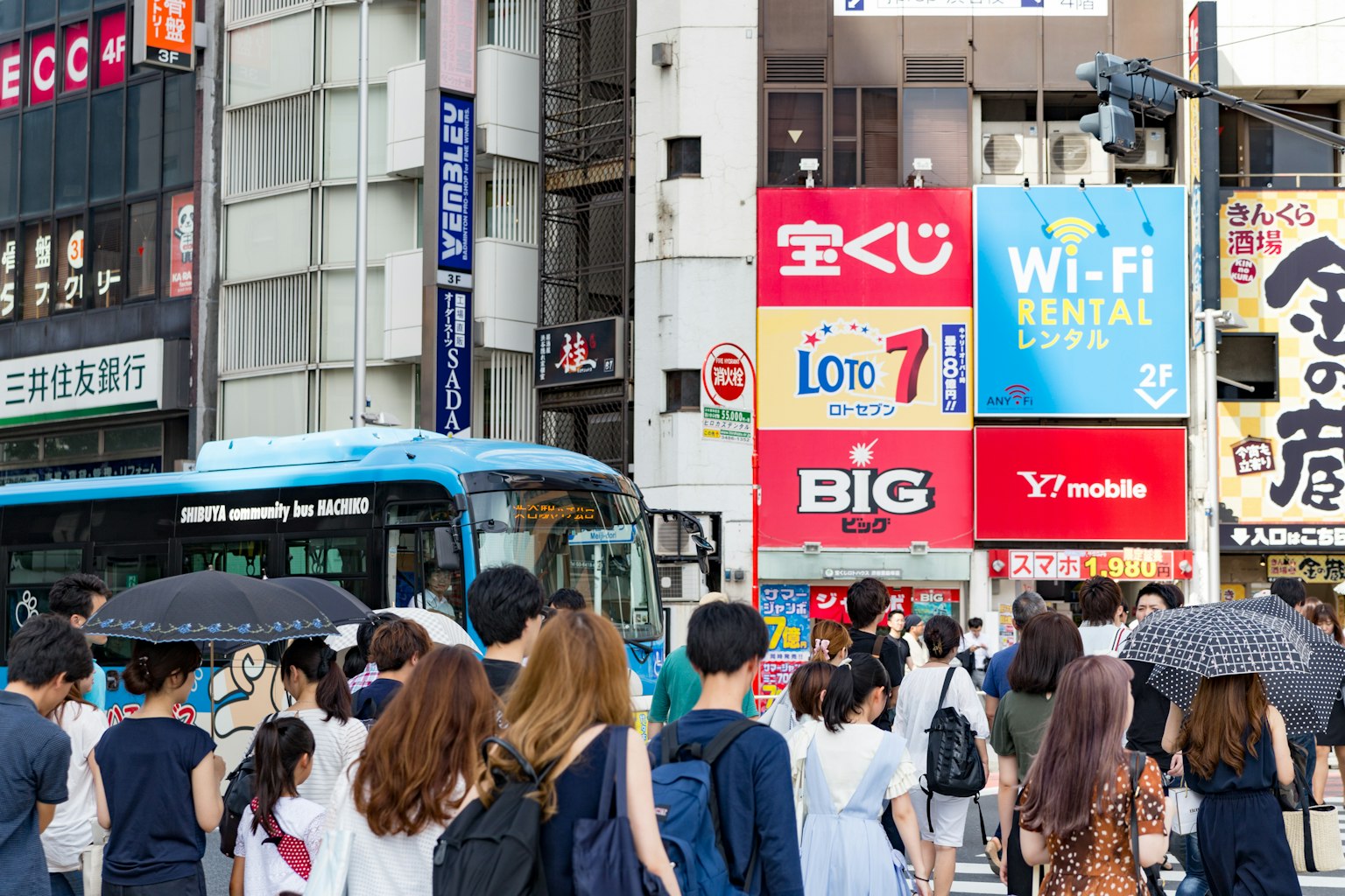 도시 풍경에서 파란색 버스와 함께 길을 건너는 군중