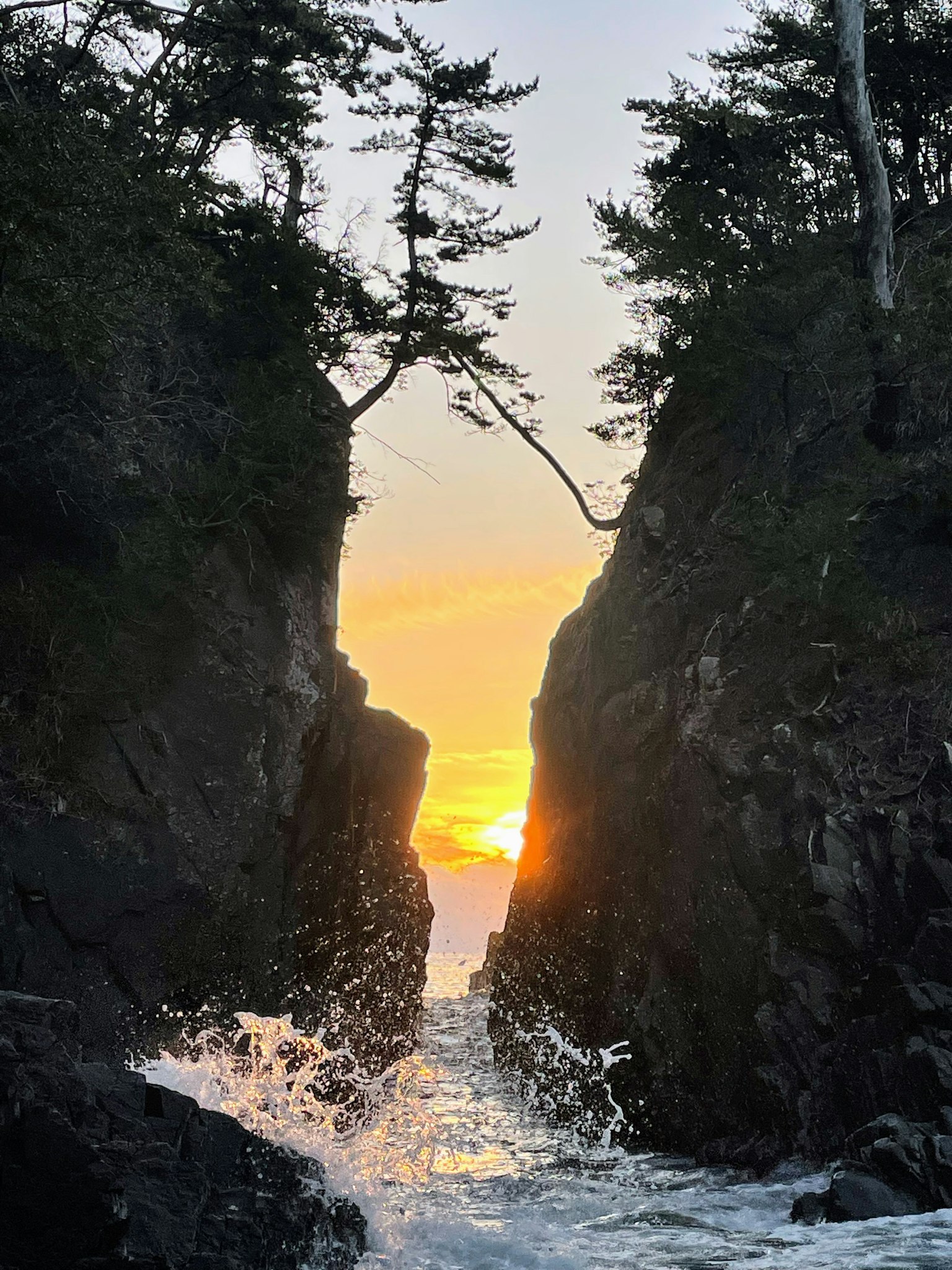 夕阳背景下岩石悬崖间的海浪