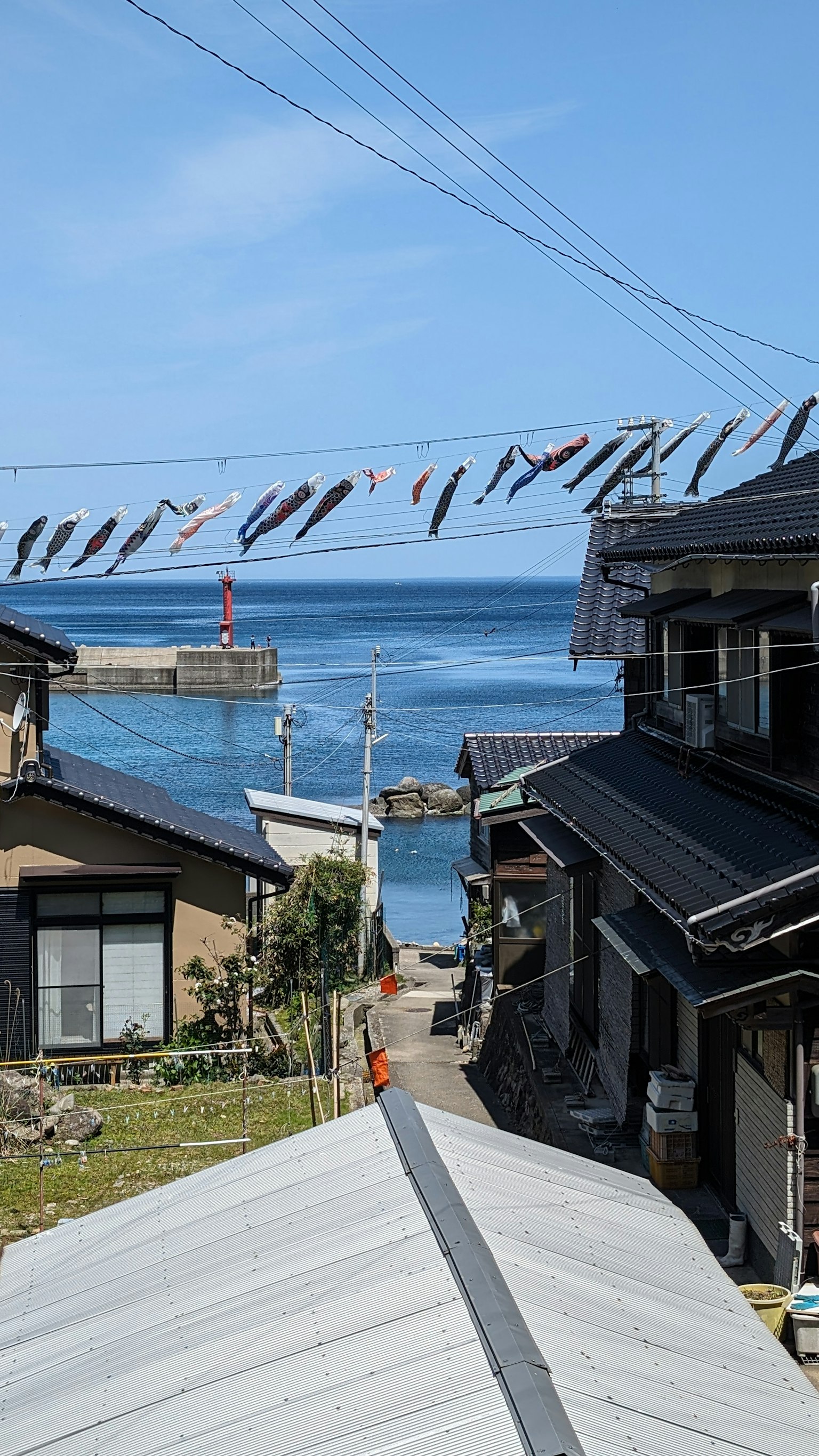Vue panoramique sur la mer bleue avec des maisons et des poissons séchant au-dessus