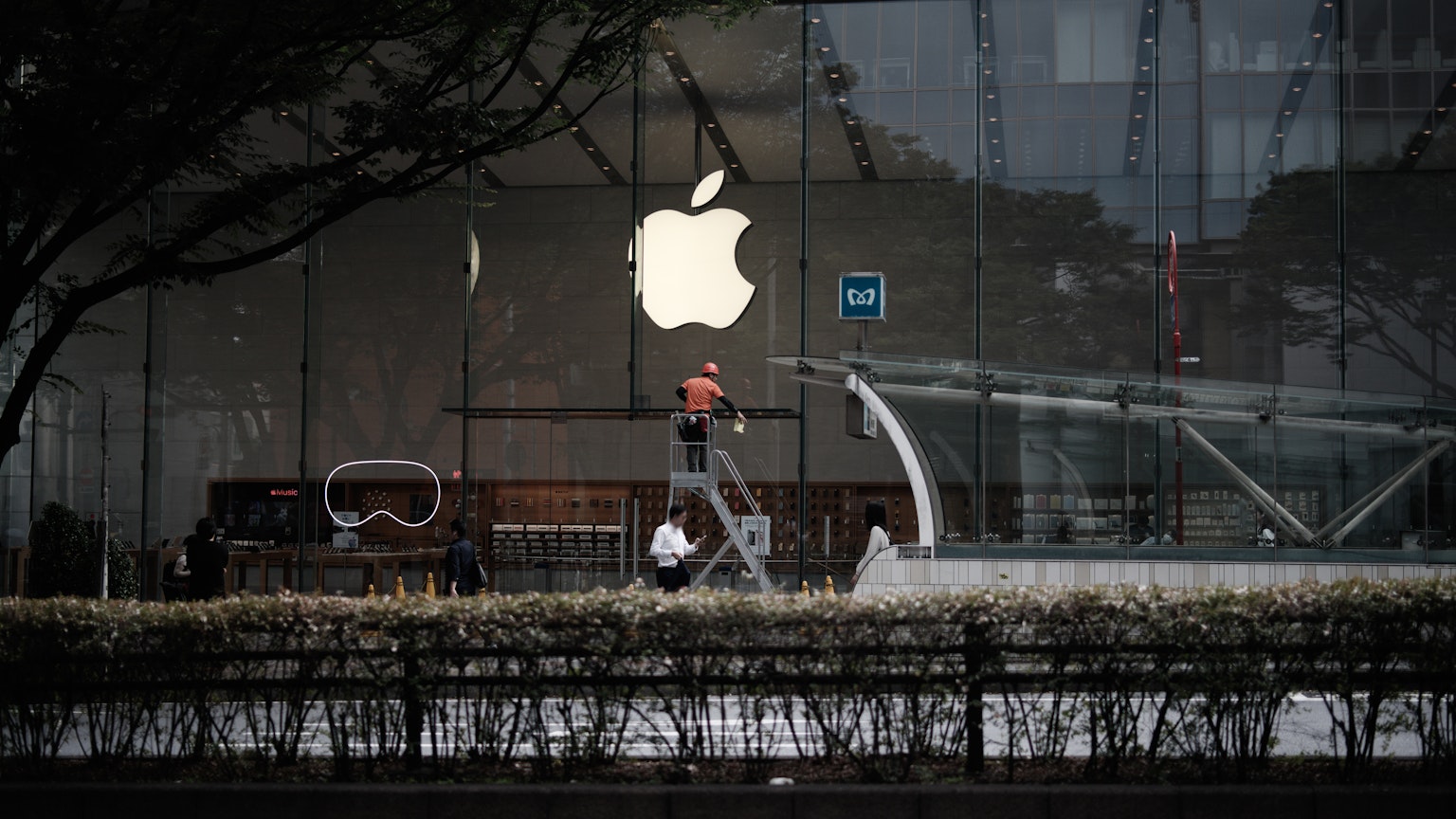 A person walking in front of an Apple store with a visible logo