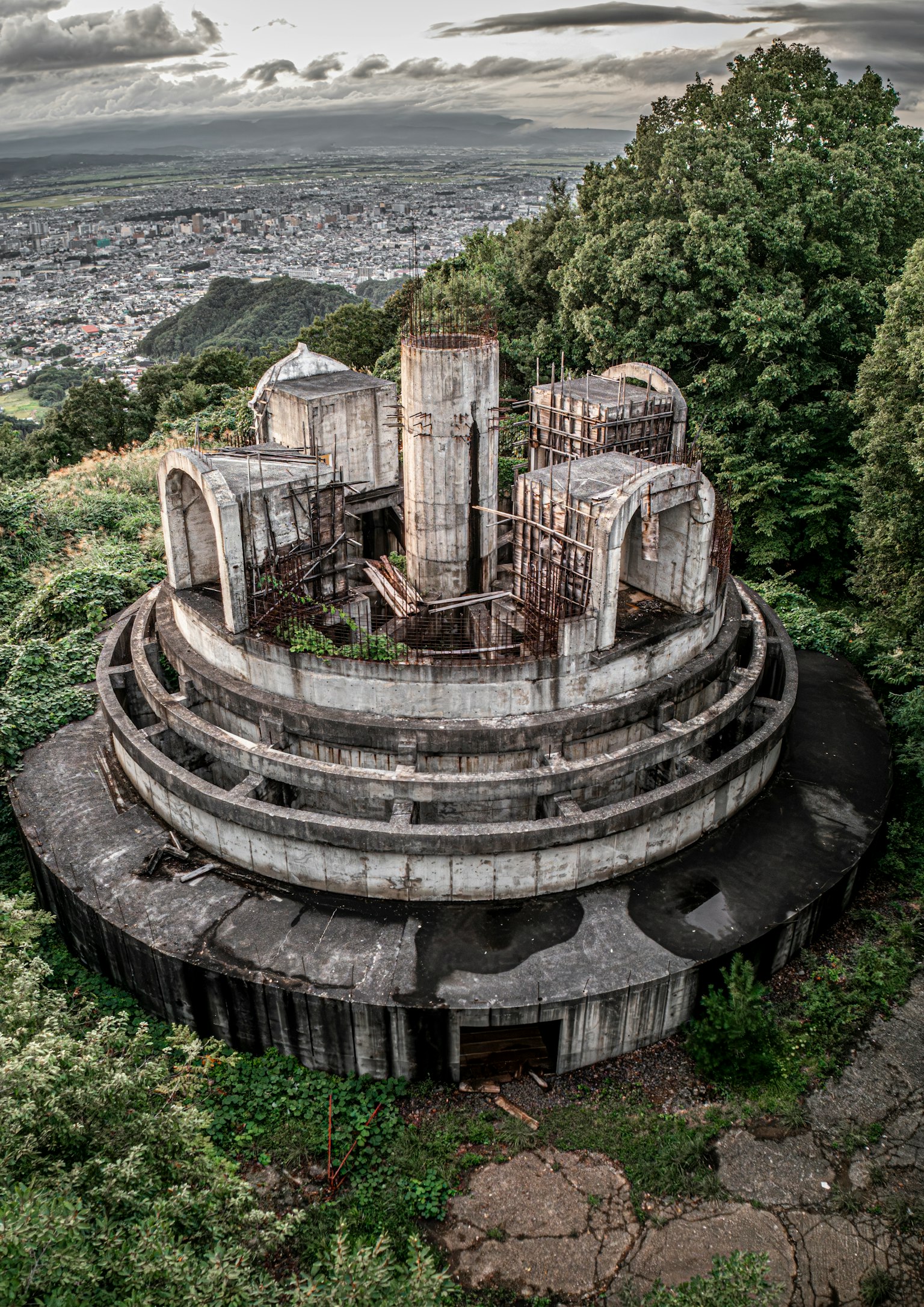 被绿树环绕的废弃圆形建筑在山坡上