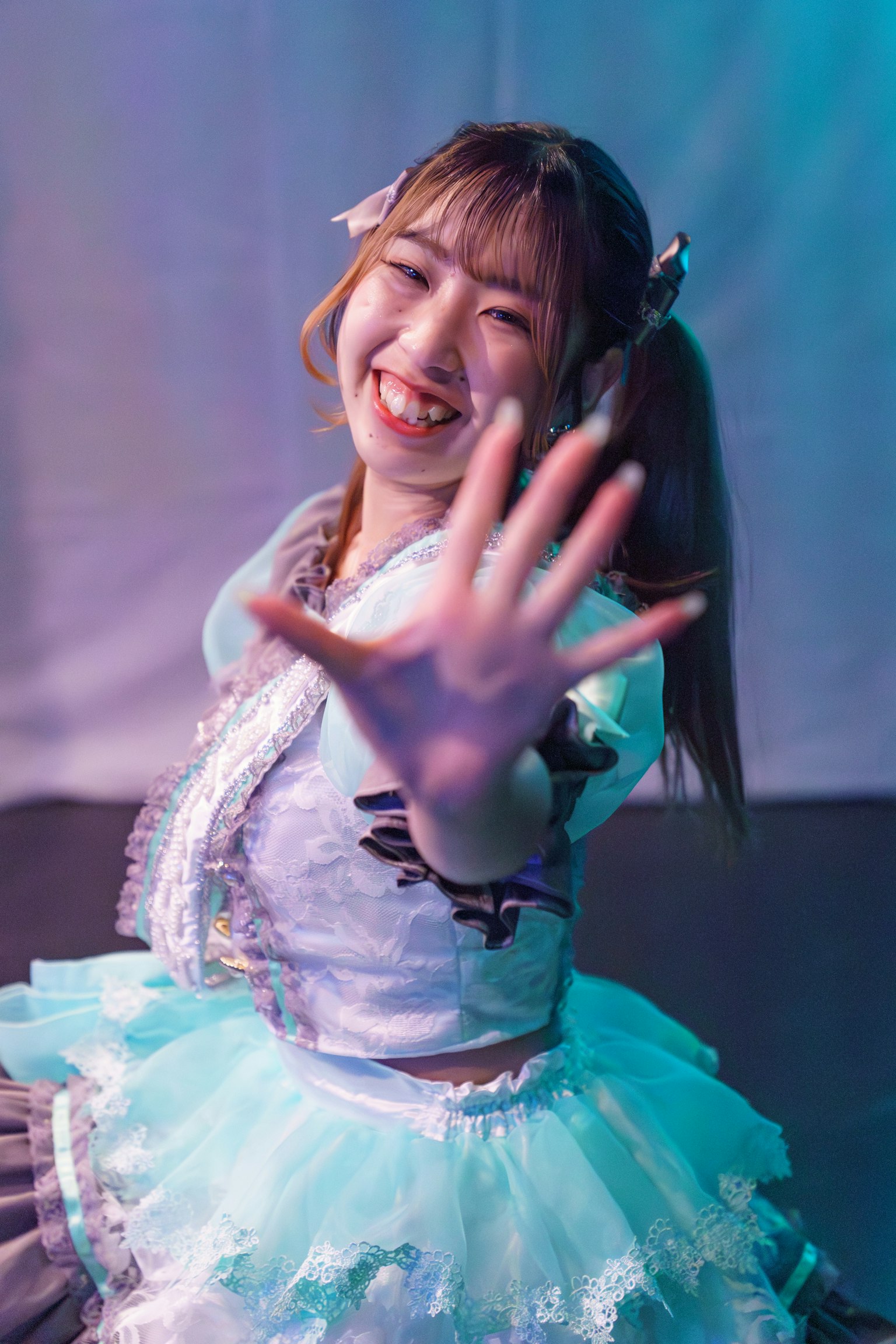 Una performer sorridente in un costume colorato che allunga la mano