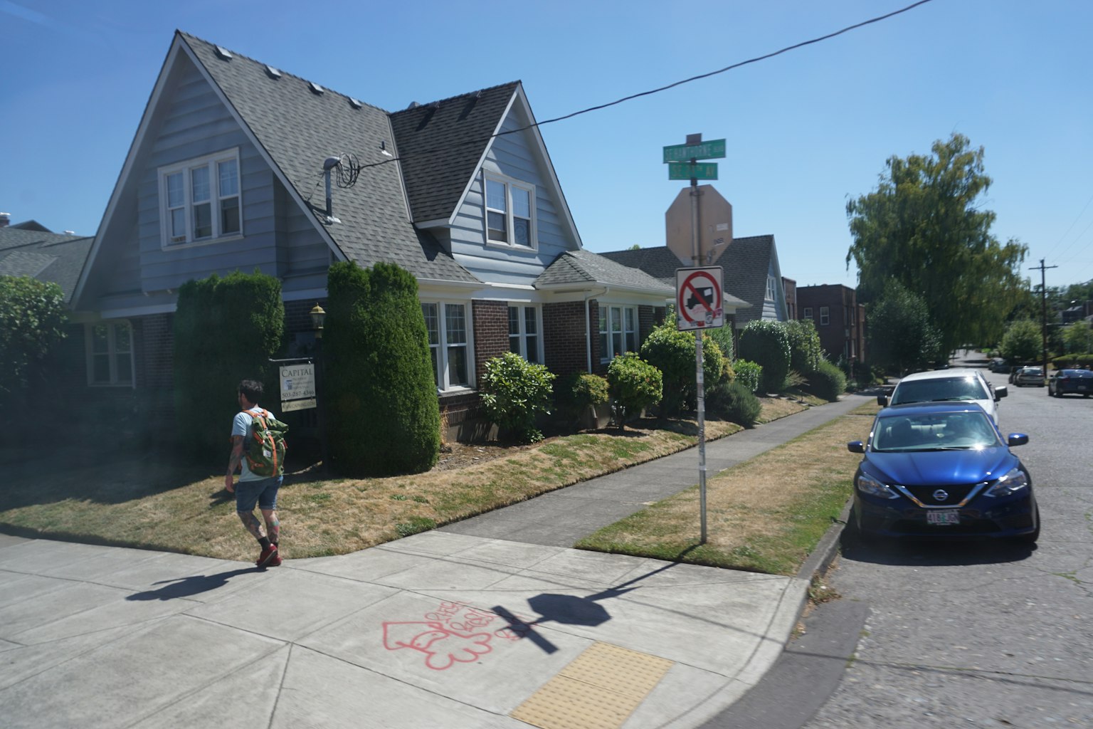 파란 차와 걷고 있는 사람의 주택가 거리 풍경