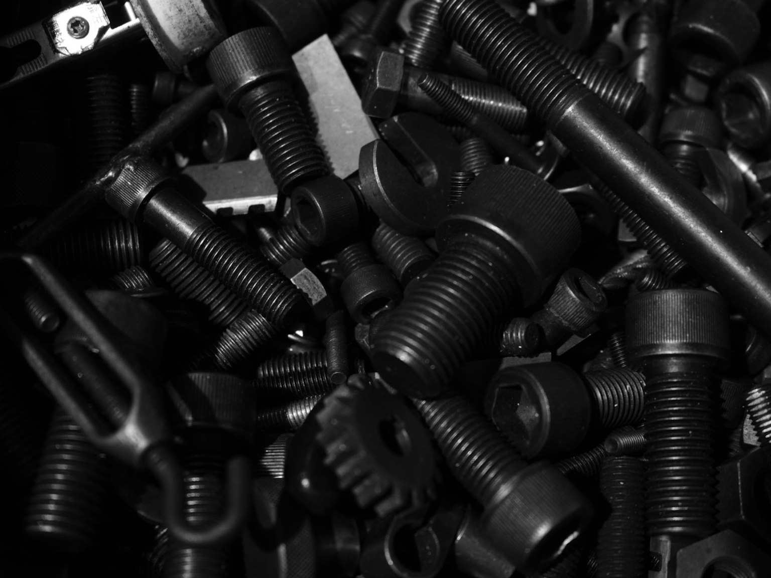 Imagen de piezas metálicas negras esparcidas que incluyen tornillos y tuercas