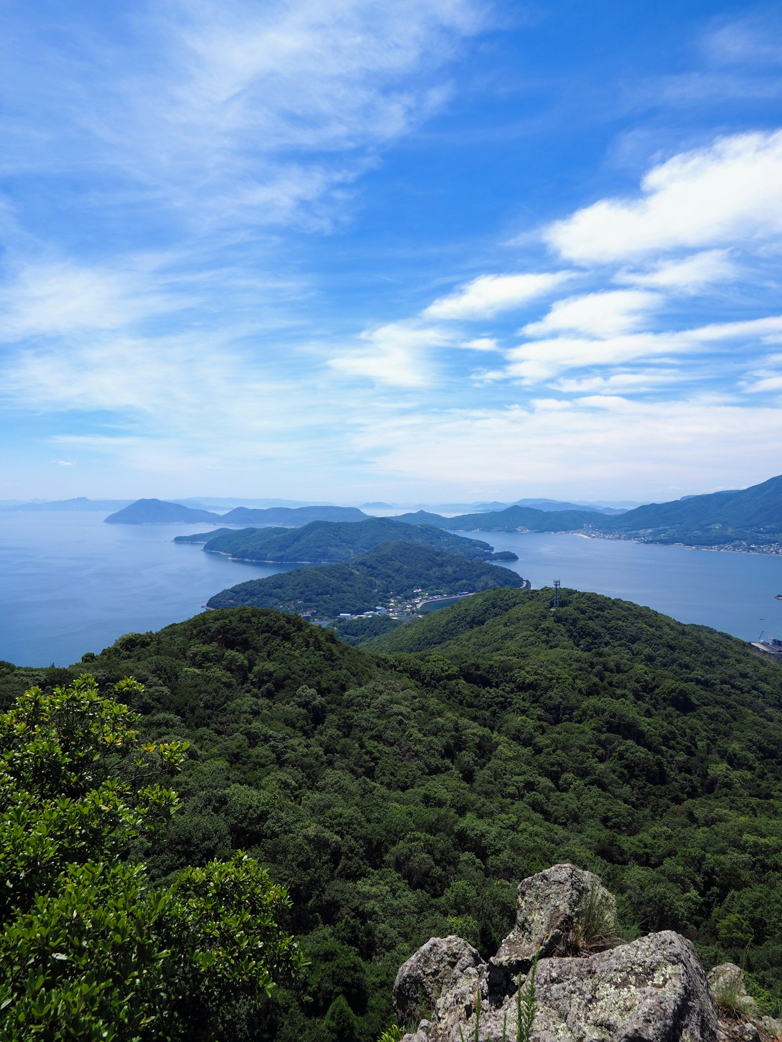 Vista escénica de montañas verdes y océano azul bajo un cielo despejado