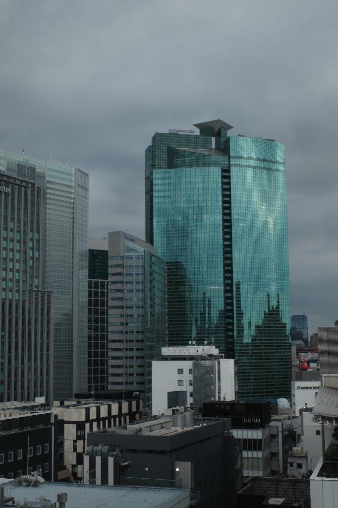 Ligne d'horizon de la ville avec un gratte-ciel en verre vert sous un ciel nuageux