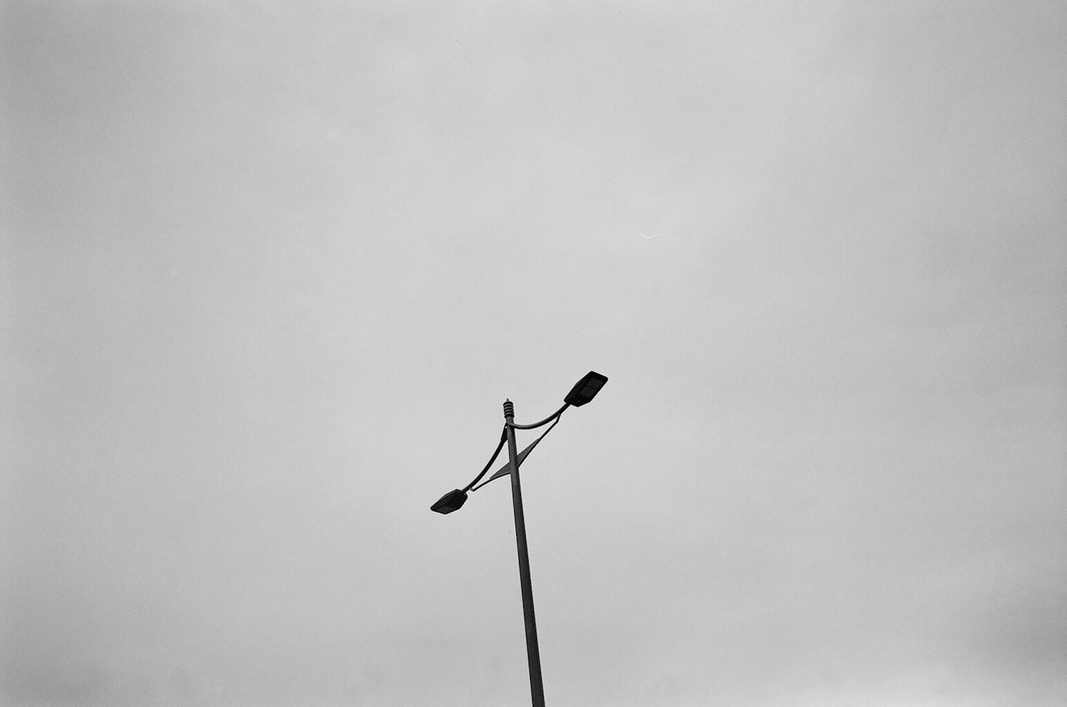 Streetlight pole with lamps against a gray sky