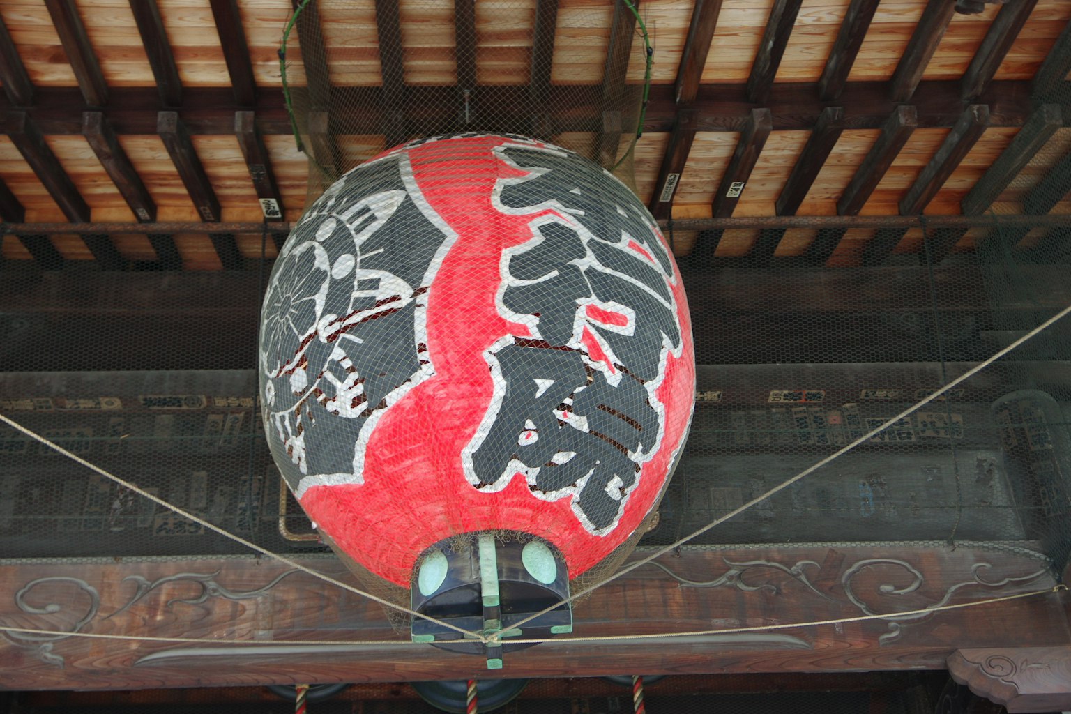 Interior de un edificio japonés tradicional con una gran linterna roja que muestra caracteres kanji