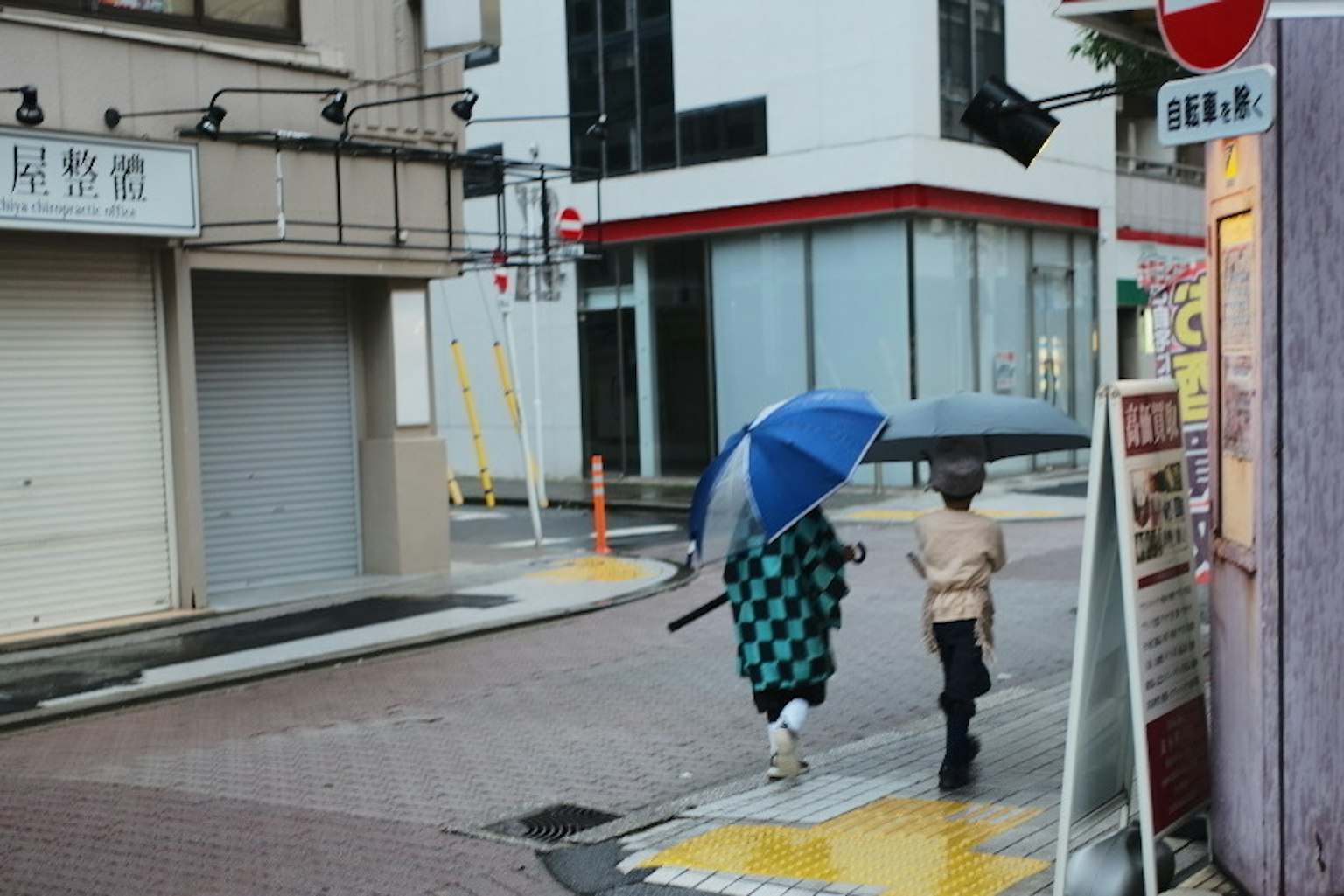 雨の中を歩く二人の人物が青い傘を持っている街角の風景