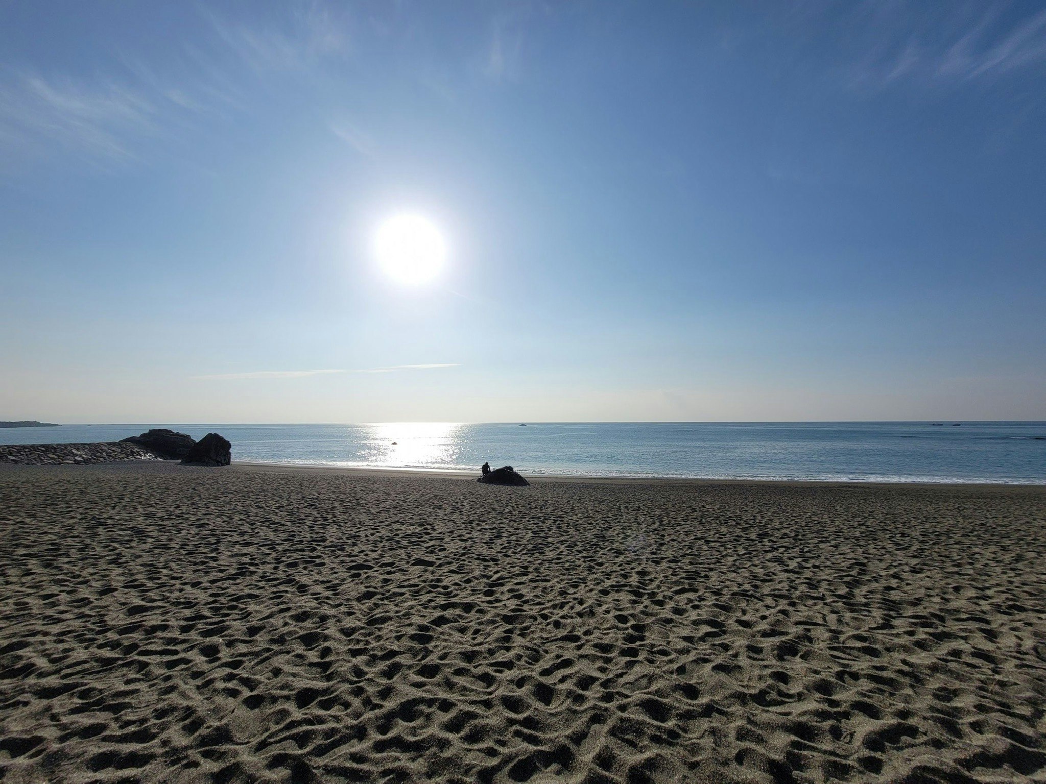 桂浜の砂浜と太陽が照らす海辺の青空