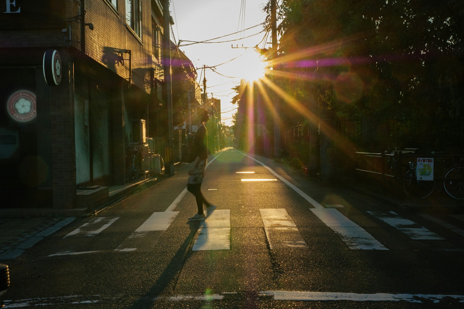 Silhouette d'une personne traversant une rue au coucher du soleil