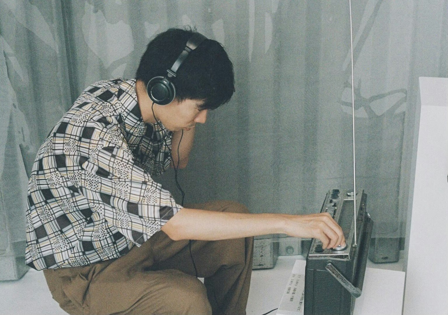 ヘッドフォンを着けた若い男性がラジオを調整している