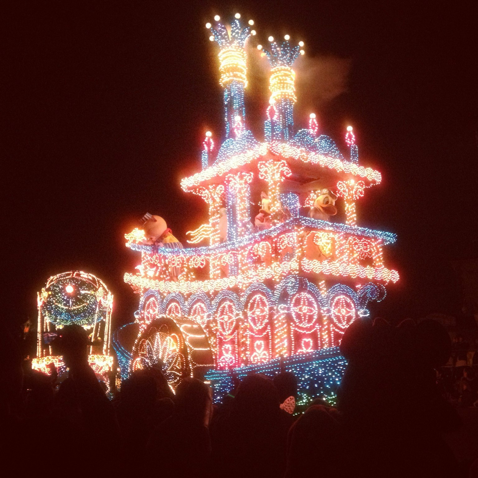 Illuminated riverboat parade float shining against the night sky