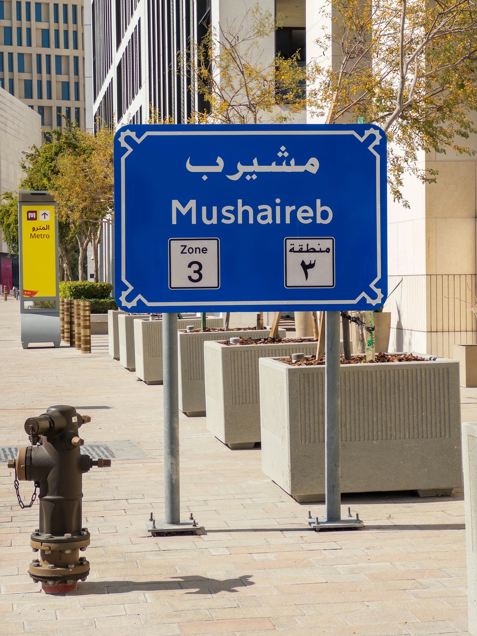 Señal azul que muestra Mushaireb con zonas y direcciones