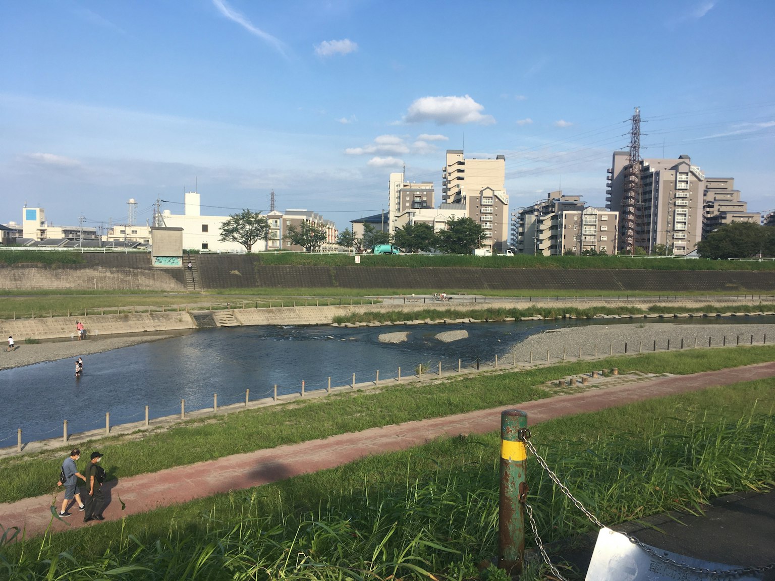 Sentiero lungo il fiume con persone che camminano e skyline della città