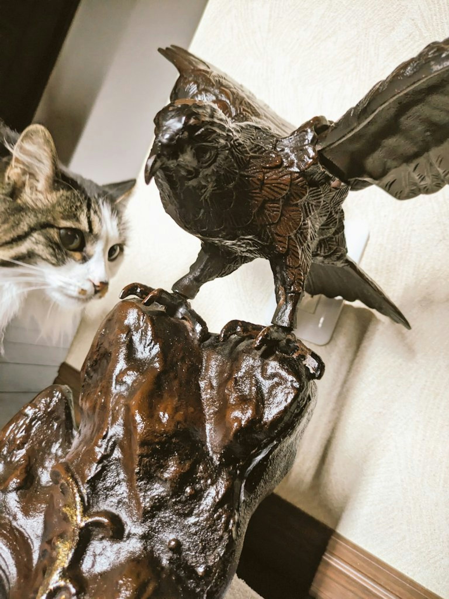 Eine Katze neben einer Skulptur eines Falken