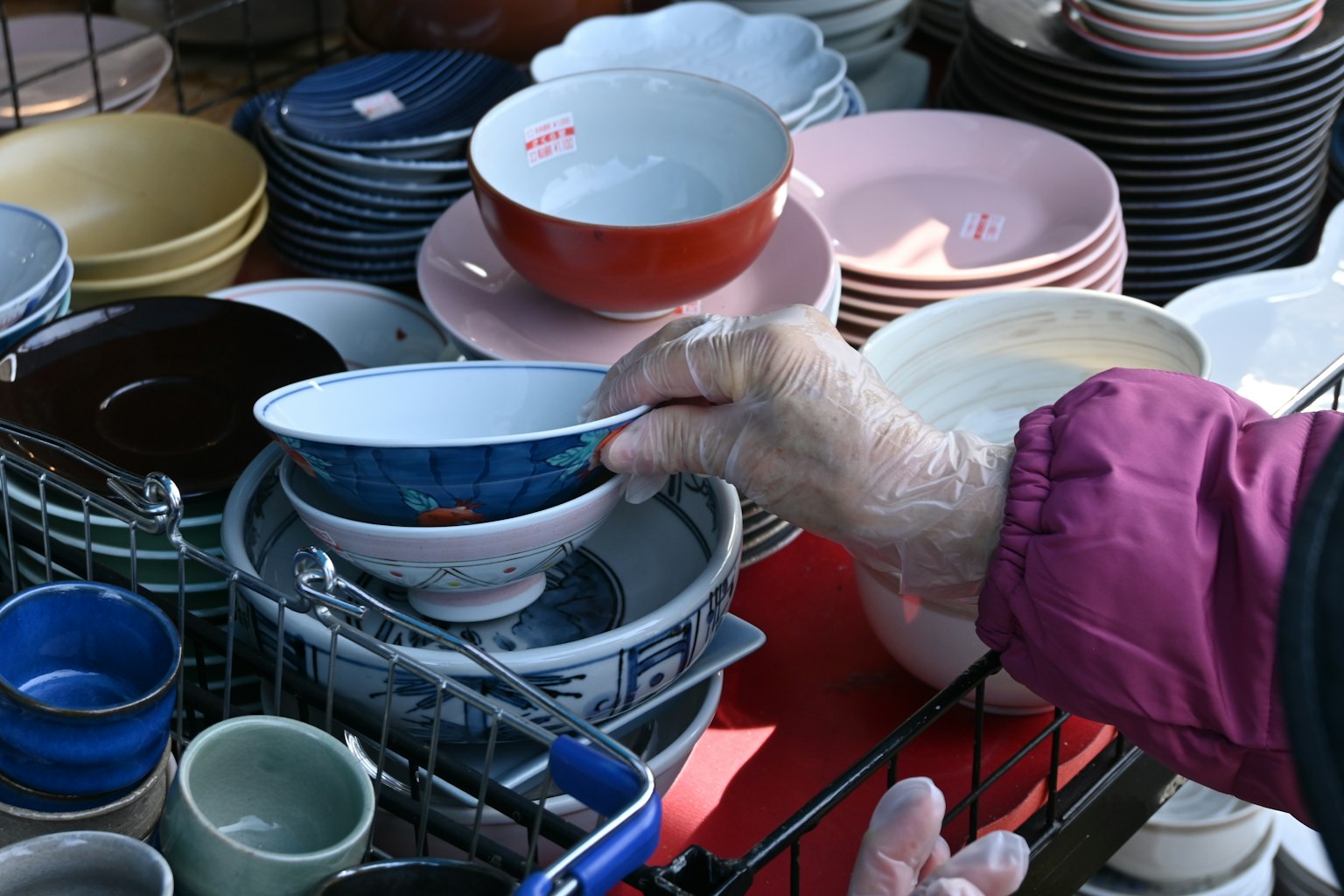 Hand selecting bowls and plates at a market