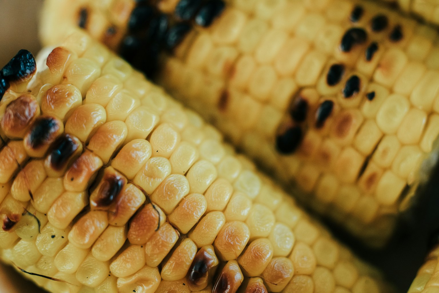 Nahaufnahme von gegrilltem Mais mit gelben Körnern und angebrannten Stellen