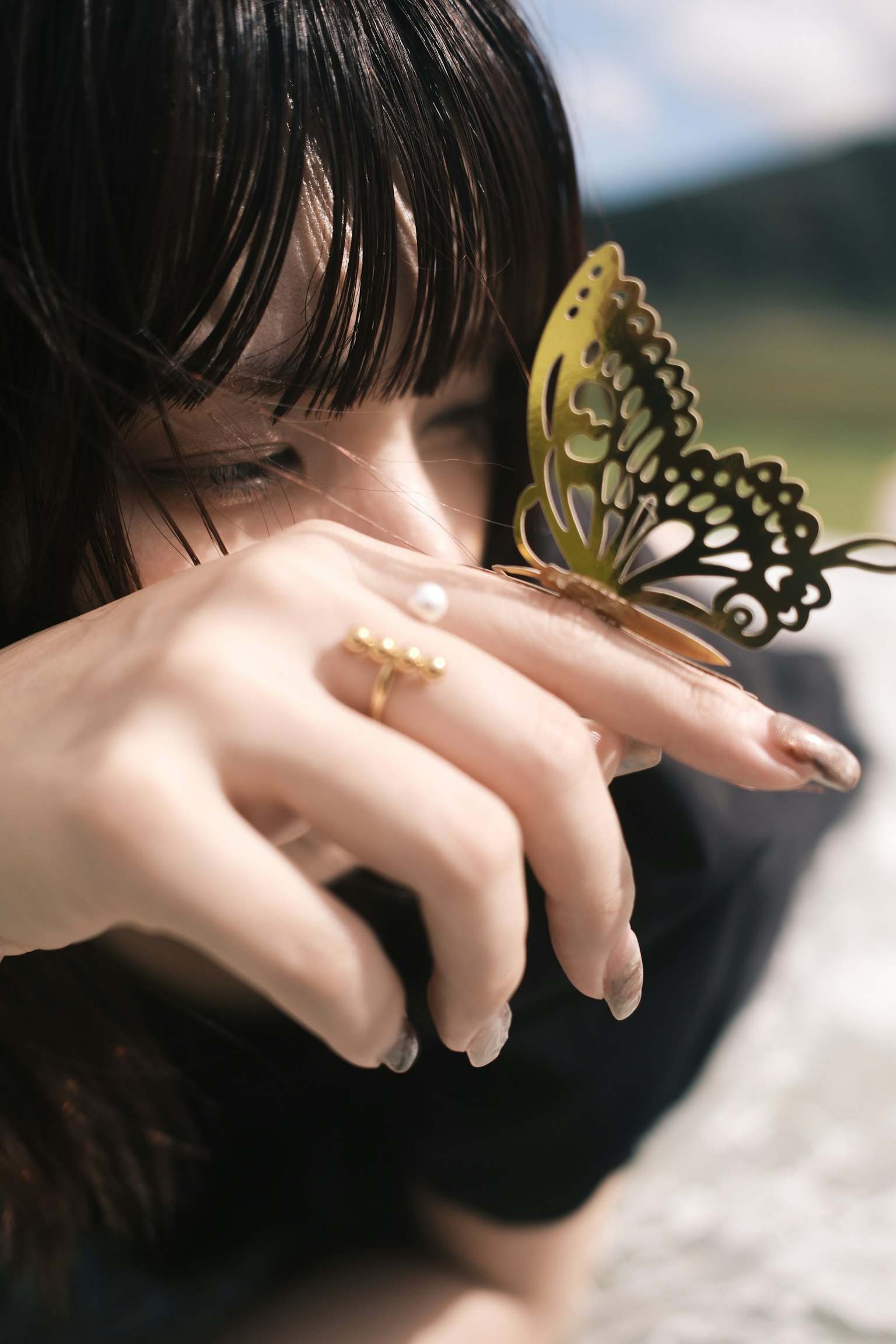 蝶が手に止まっている女性の横顔と自然の背景