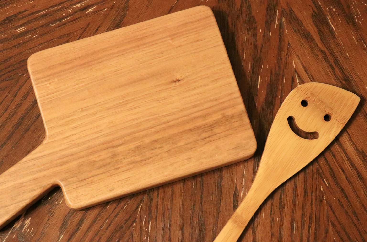 Papan pemotong kayu dan spatula kayu tersenyum di atas meja