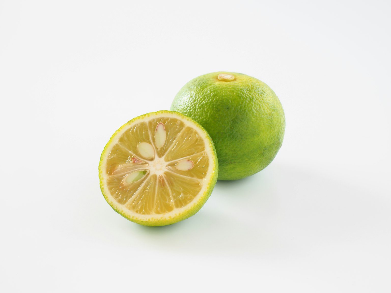 Un lime verde e un lime tagliato a metà su uno sfondo bianco