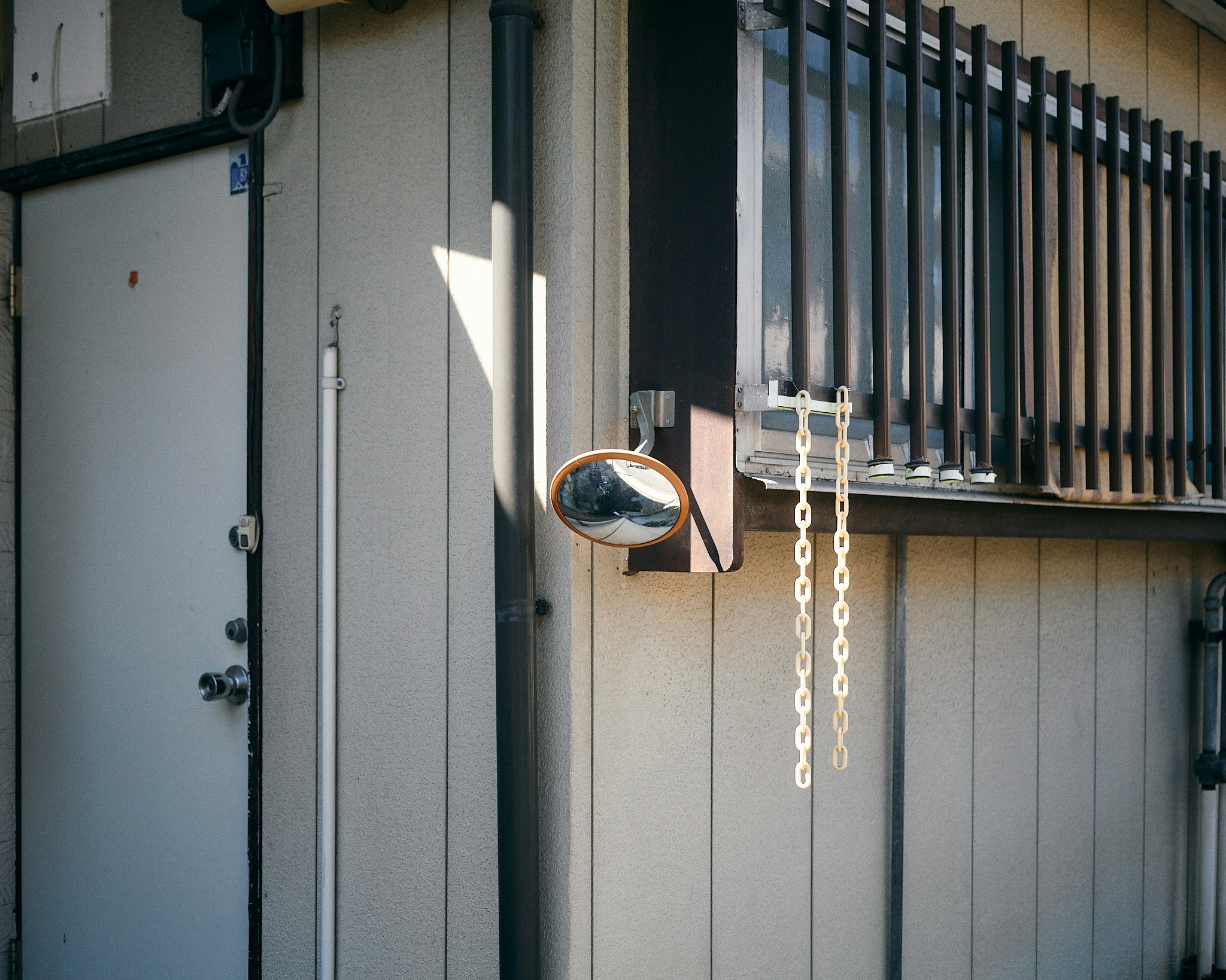 round mirror and metal chain on an alley exterior wall