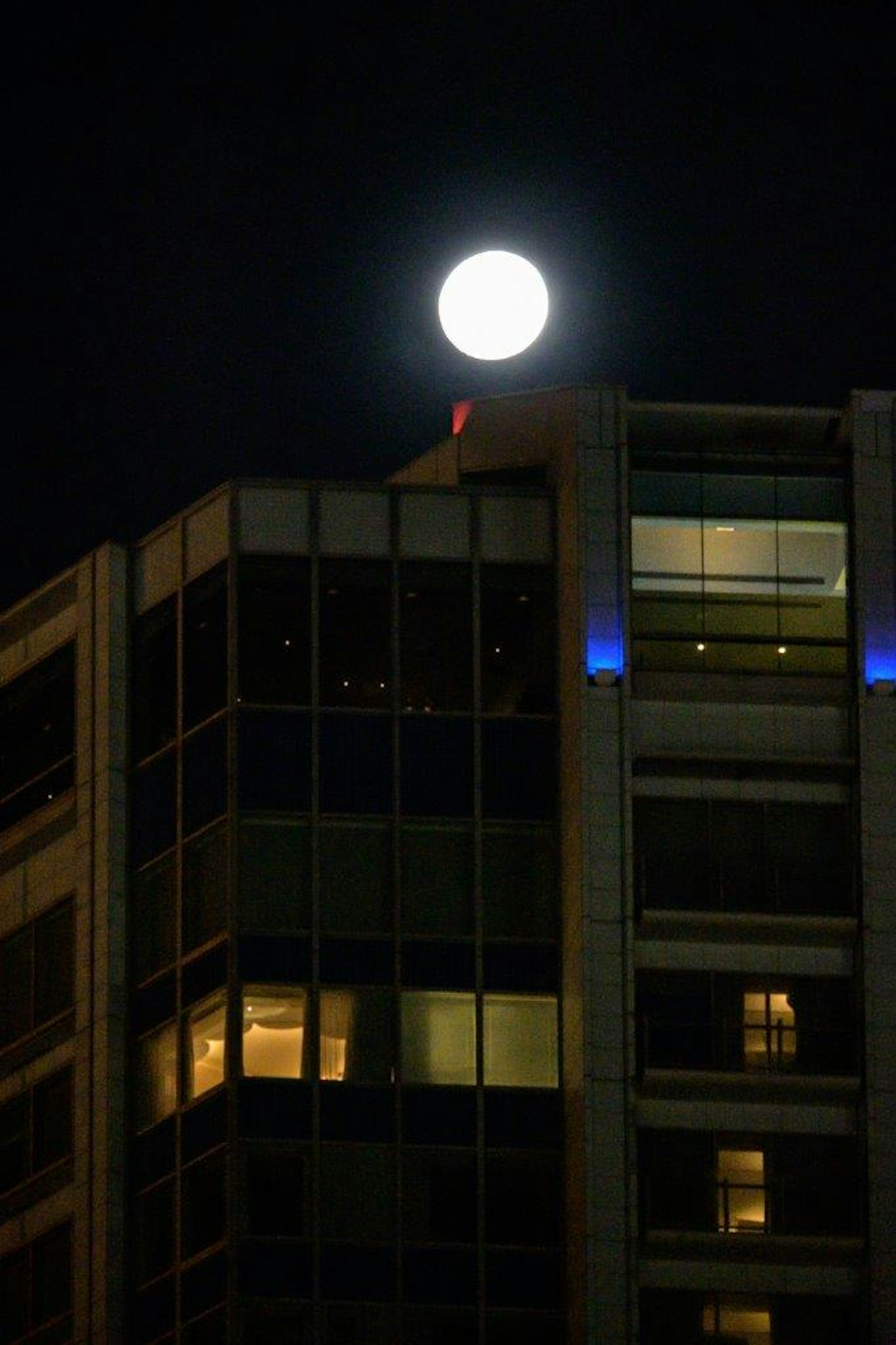 夜空中的明亮圆月与现代摩天大楼
