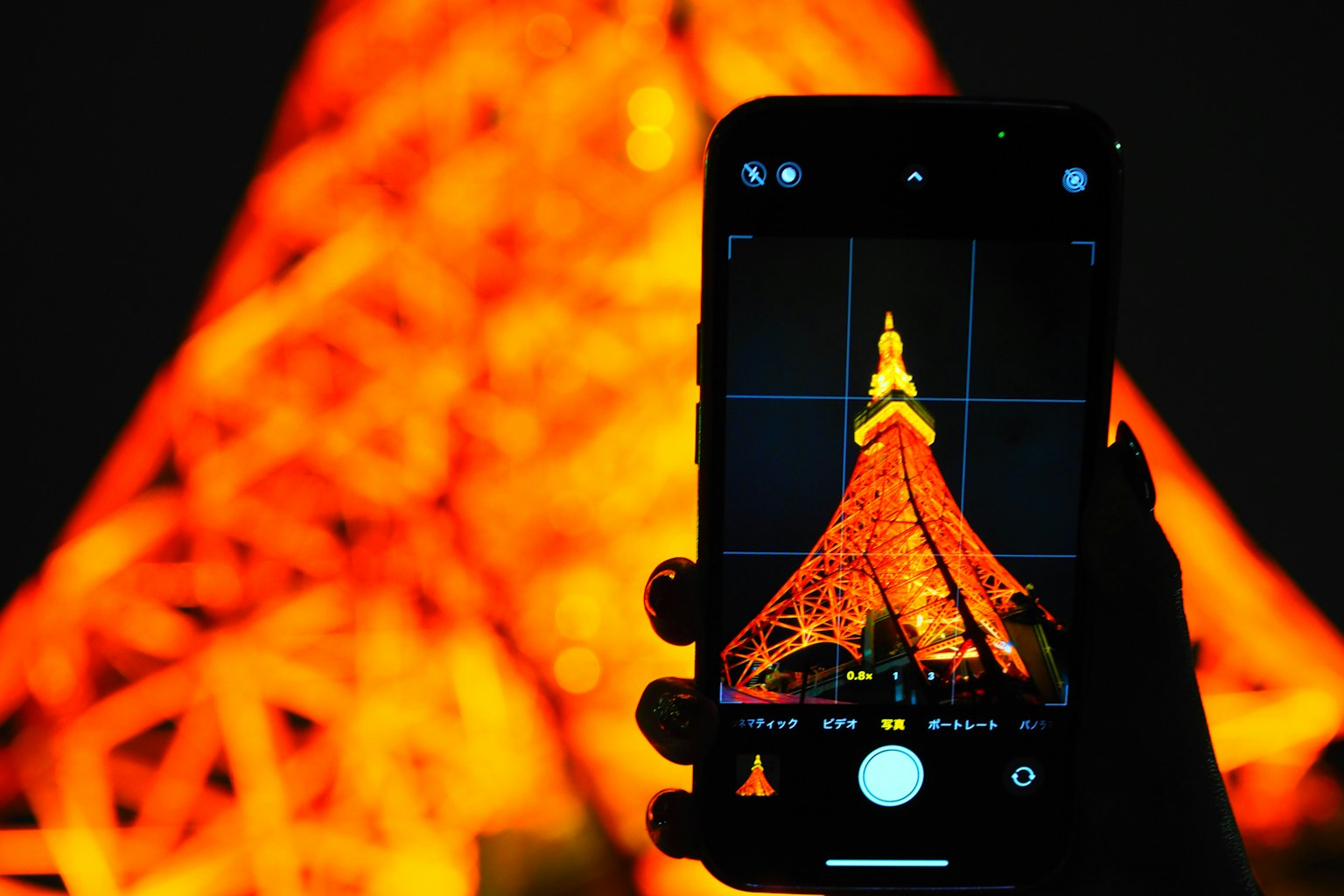 Mano che tiene uno smartphone che cattura la Torre di Tokyo di notte