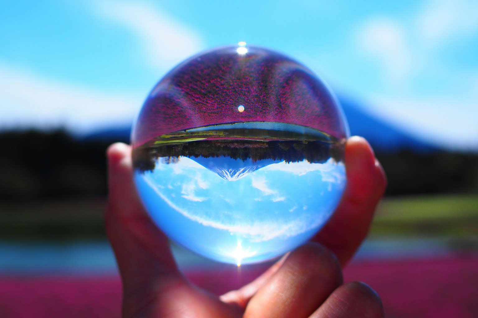 Una sfera di cristallo che riflette un paesaggio scenico tenuta in una mano