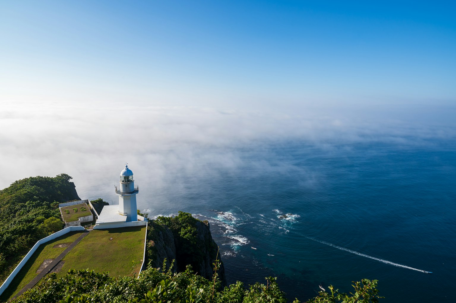 Malersicher Blick auf einen Leuchtturm vor blauem Himmel und Ozean