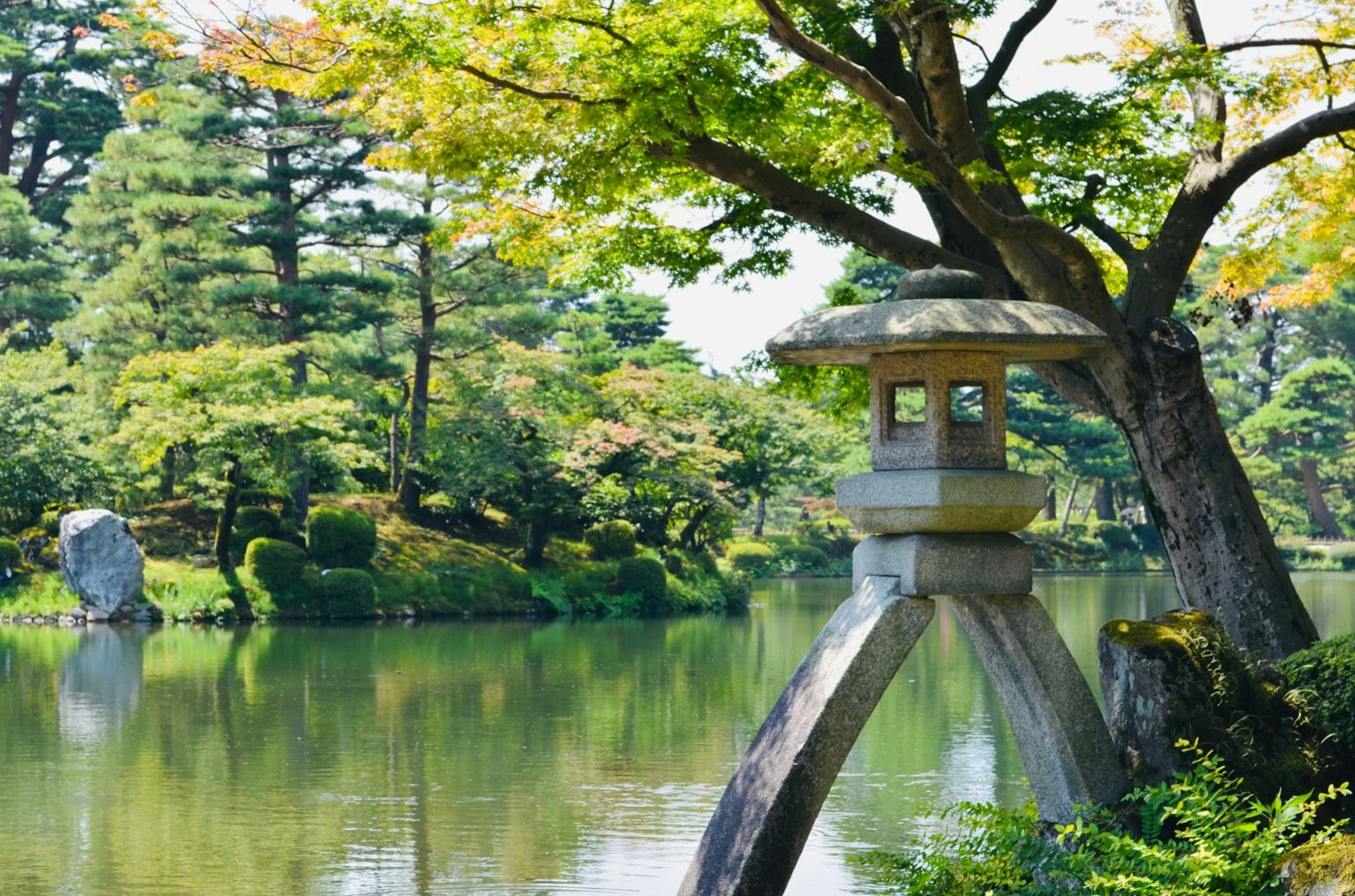 Lanternes en pierre au bord d'un étang serein dans un jardin japonais avec feuillage d'automne