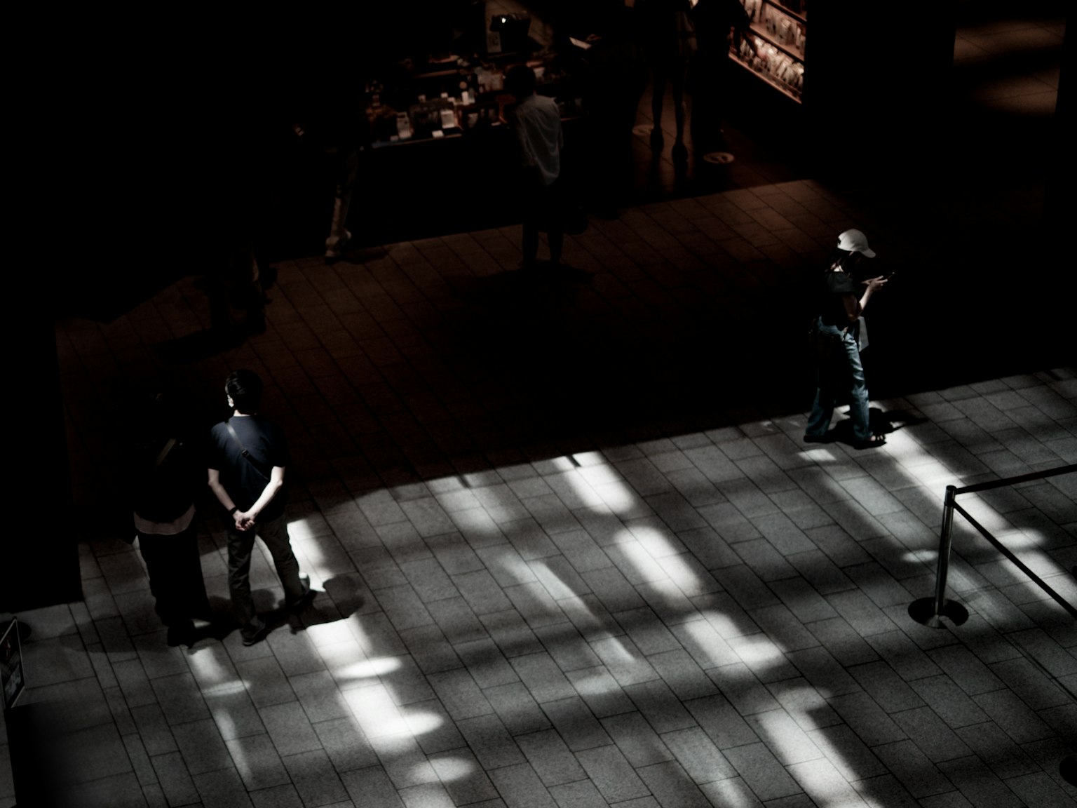 人們在現代建築中站著,光線透過黑暗空間