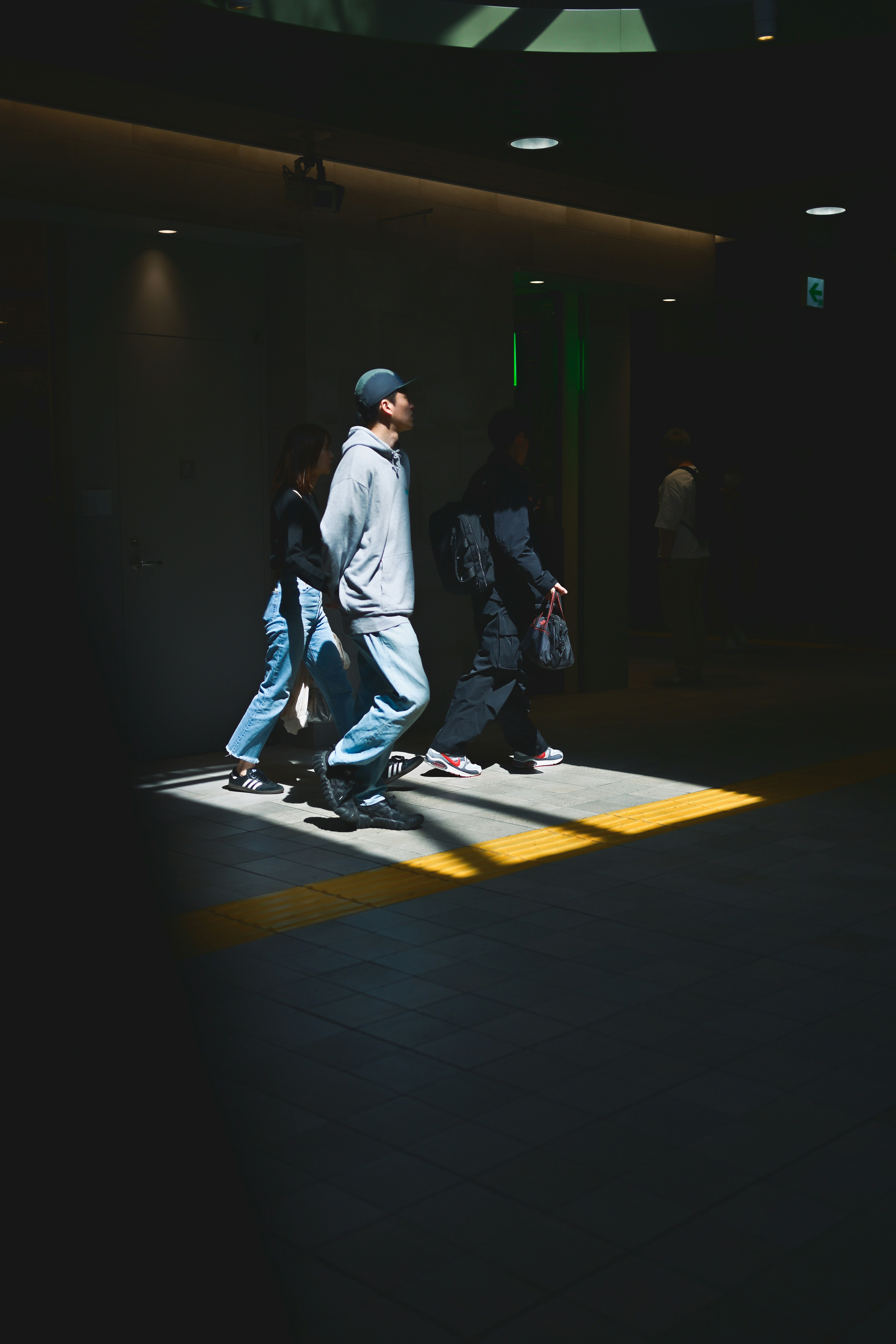 地下通道裡行走的人物剪影與黃色盲道