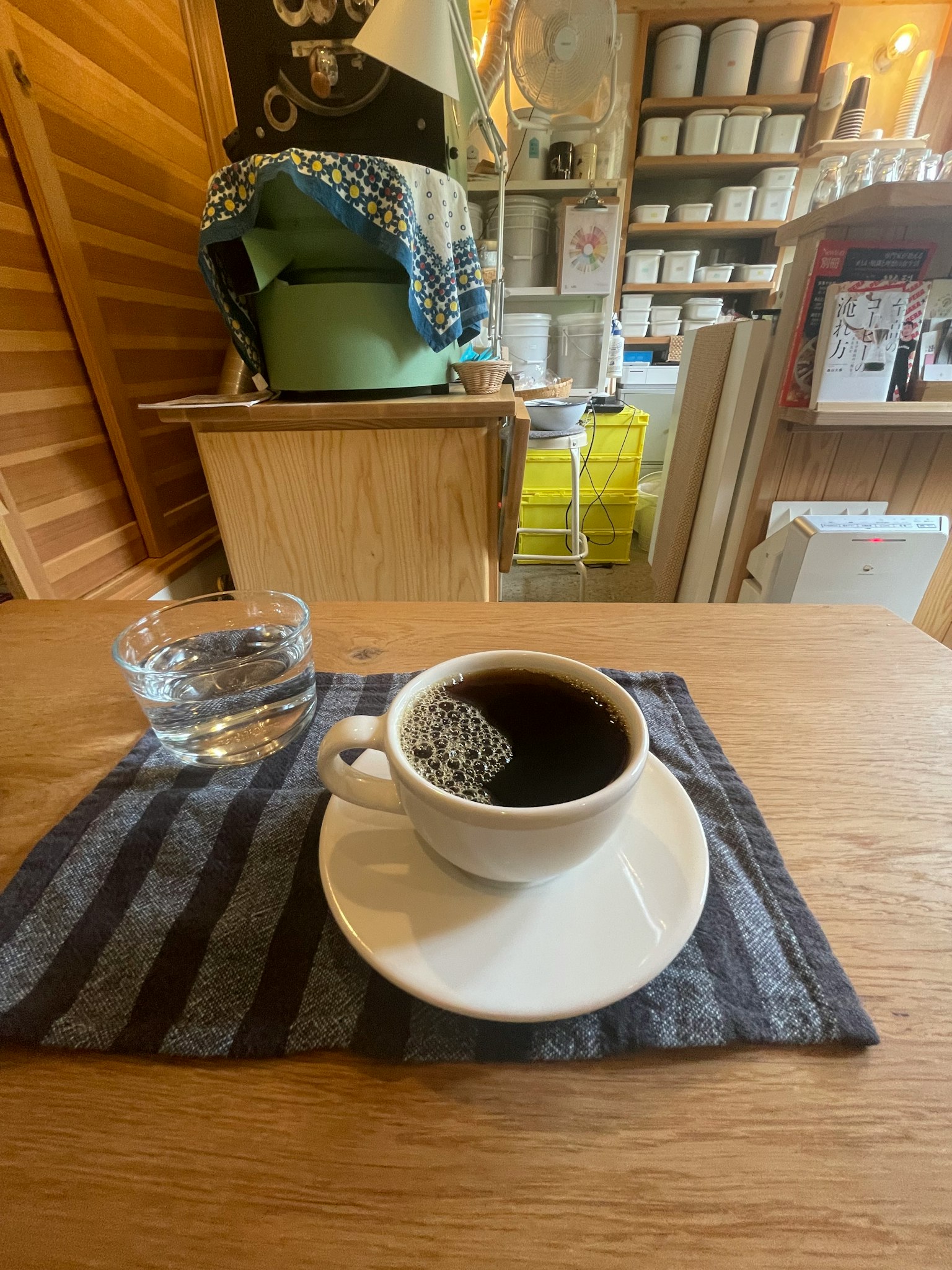 Eine einfache Café-Szene mit einer Tasse Kaffee und einem Glas Wasser auf einem Holztisch
