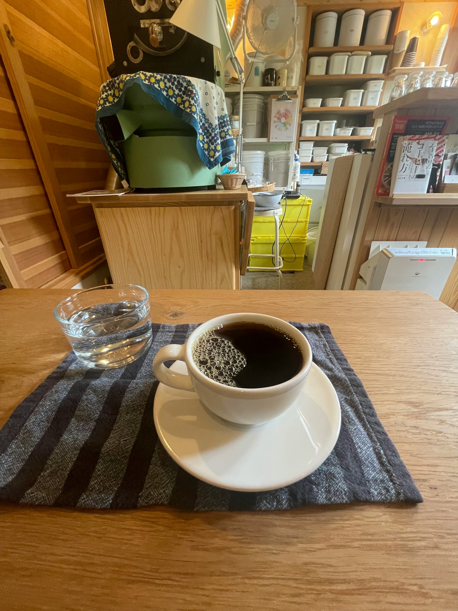 テーブルの上に置かれたコーヒーカップと水のグラスがあるシンプルなカフェの風景