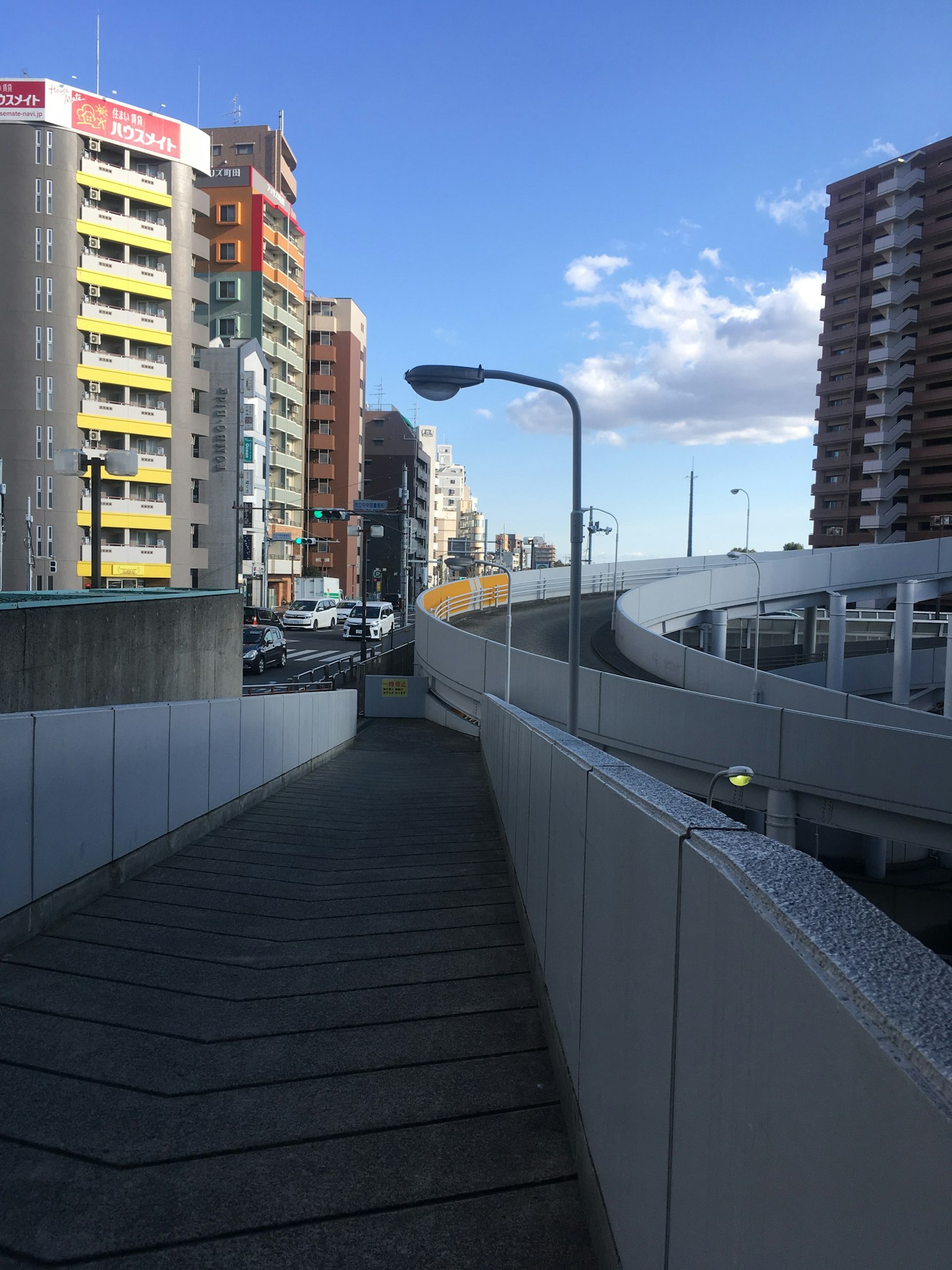 Gebogene Gehweg entlang urbaner Gebäude und blauer Himmel